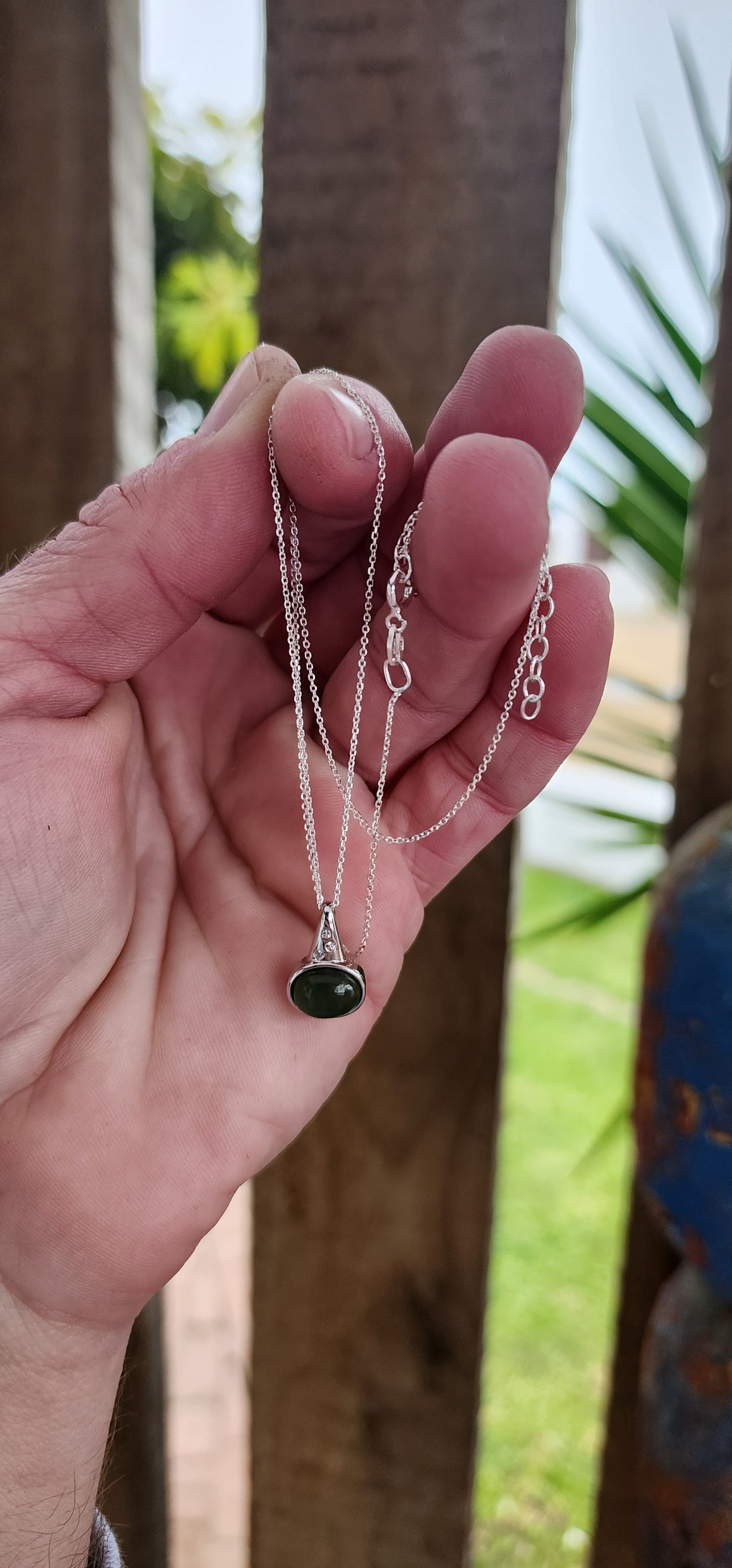 Sterling Silver pendant bezel/tube set with a Oval Shaped Green Nephrite Jade Cabochon , suspended from a Modernist Triangular shape that has been flush set with 3x CZ Gemstones.Comes fitted on a adjustable length Sterling Silver chain.