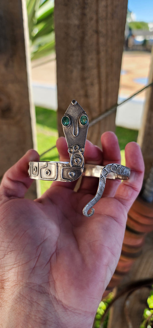 Vintage Egyptian Revival Arts and Crafts movement upper arm Serpent bracelet - Crafted in Sterling Silver with a embossed patterned body/tail, the Serpents eyes have been set with Natural Oval cut Emeralds in bezel/tube settings.