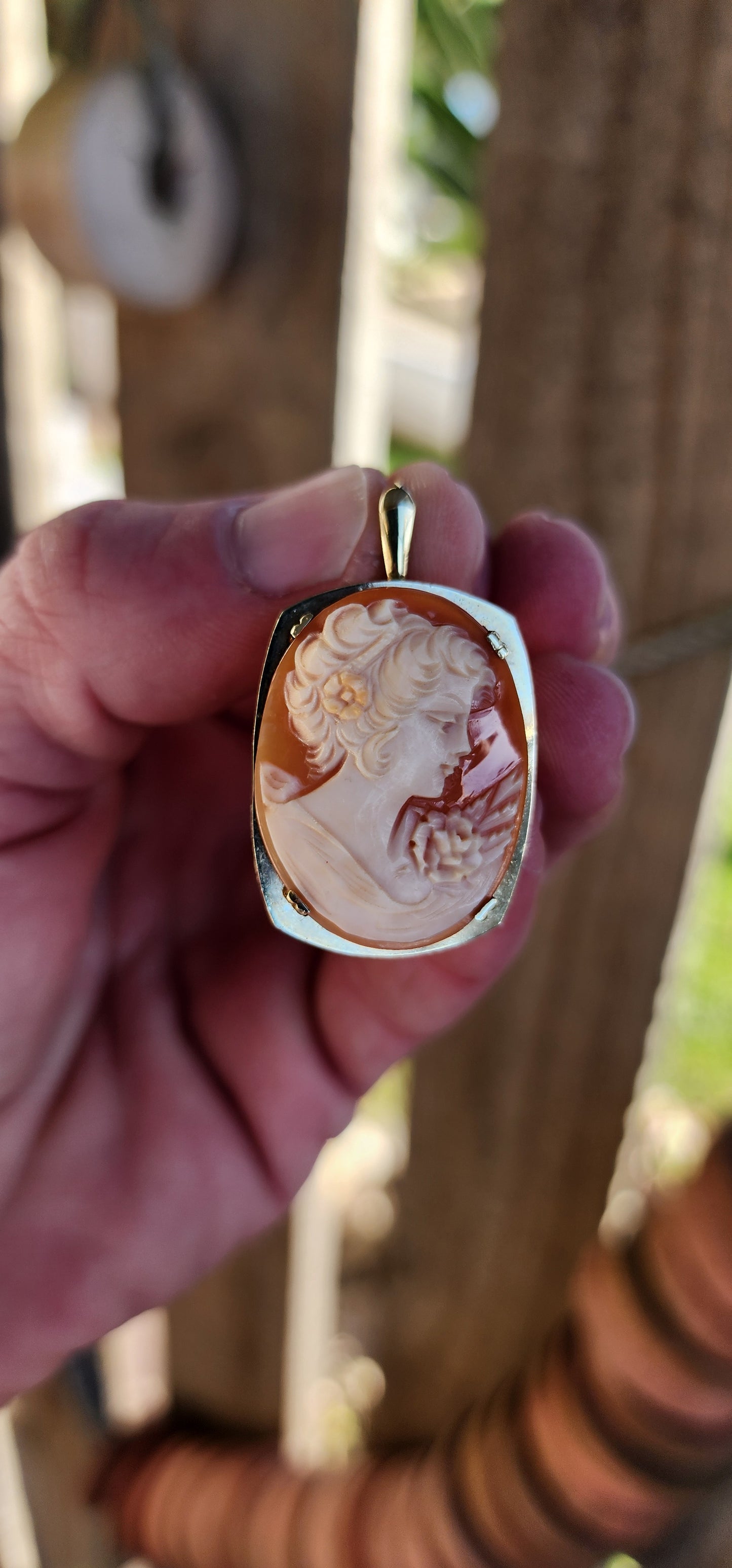 Beautiful Vintage hand carved Shell Cameo brooch/Pendant. The masterfully carved Cameo depicting a portrait of a elegant right facing lady with a flower in her hair .The Cameo has been prong set in a 10ct Yellow Gold Rounded Rectangular shape frame.