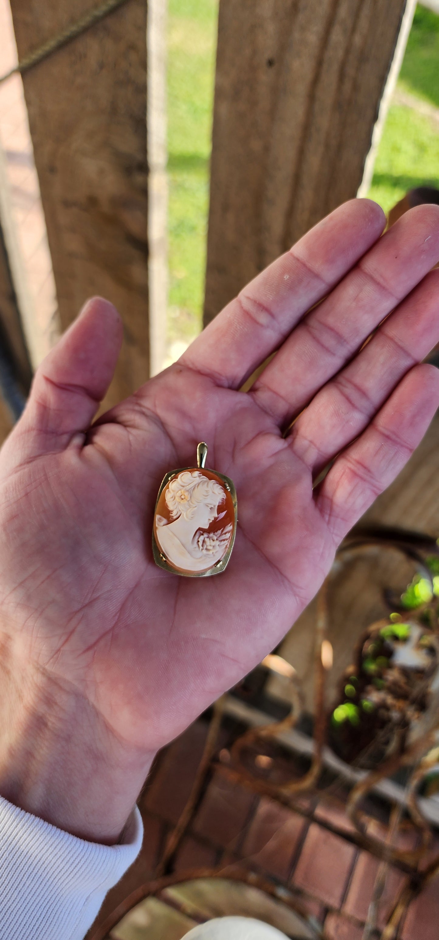 Beautiful Vintage hand carved Shell Cameo brooch/Pendant. The masterfully carved Cameo depicting a portrait of a elegant right facing lady with a flower in her hair .The Cameo has been prong set in a 10ct Yellow Gold Rounded Rectangular shape frame.