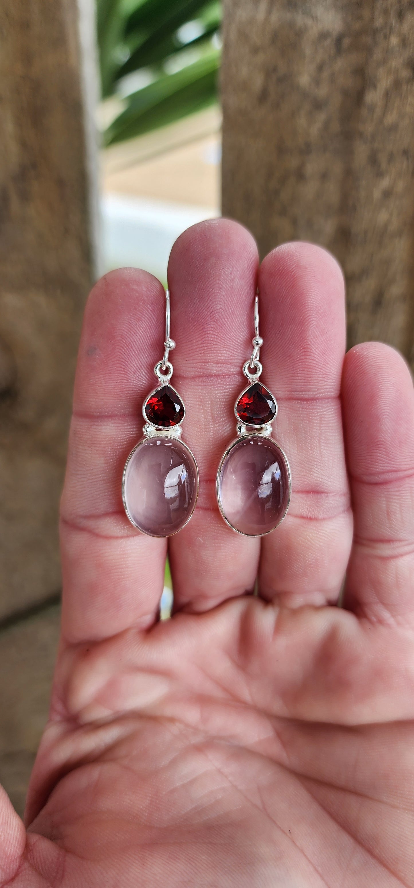 Elegant pair of Sterling Silver drop earrings.The earrings feature generous in size Oval Rose Quartz cabochon drops that are bezel/tube set ,suspended from bezel/tube set faceted Trilion cut Garnet Gemstones.