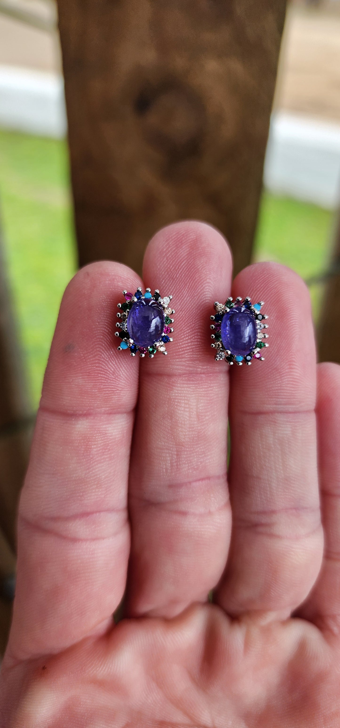 Extremely beautiful and elegant pair of Sterling Silver stud earrings - Each Earring claw set with a Natural Tanzanite Cabochon in the centre and surrounded by a muticolor Gemstones Haló frame of small Round cut Gemstones.