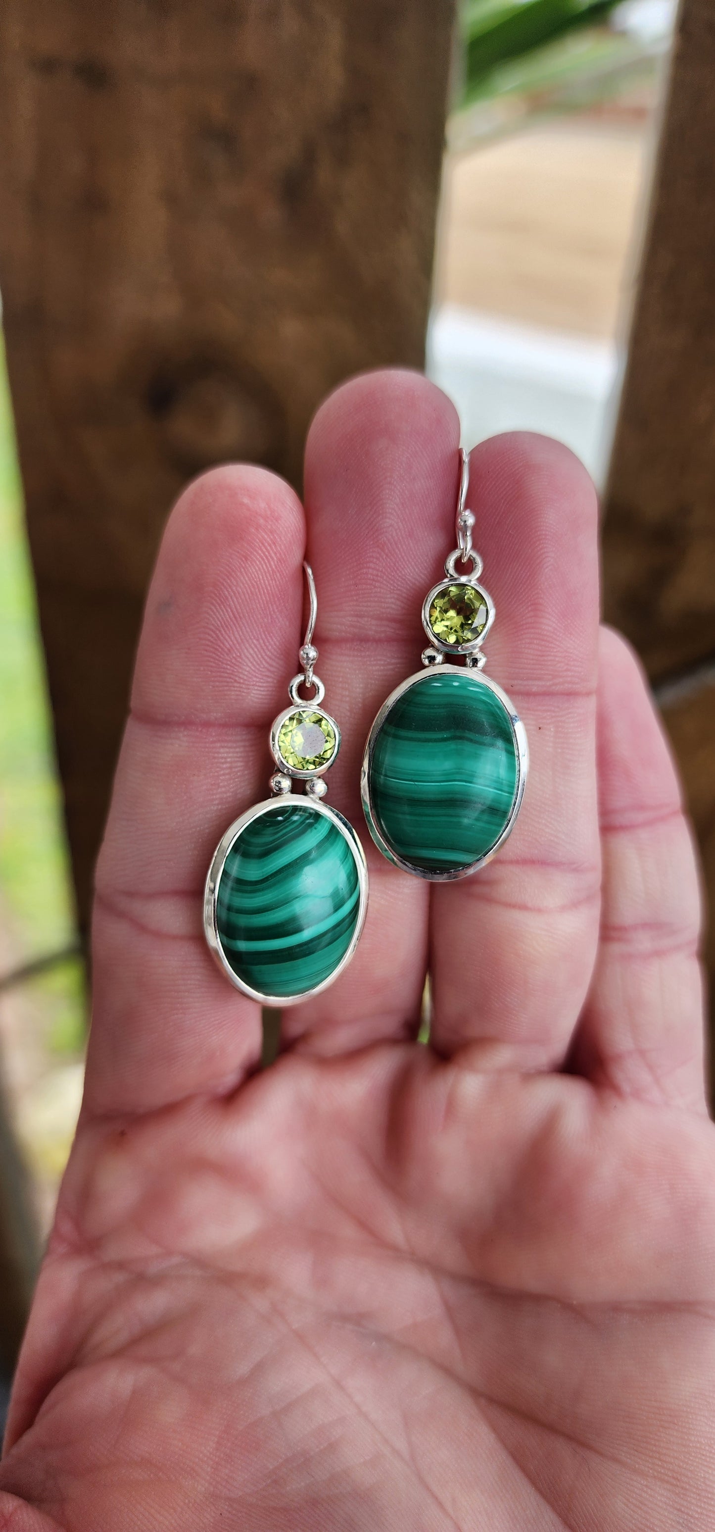 These lovely Sterling Silver dangle earrings are the perfect go to for any jewelry collection. They feature bezel/tube set oval Malachite cabochons suspended from Round faceted cut Peridot Gemstones in bezel/tube settings.