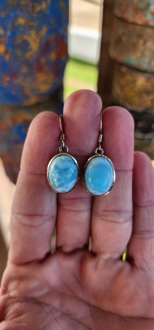 Gorgeous Larimar drop earrings .Oval cut Larimar Cabochons embedded in Sterling Silver tube settings , suspended from Sterling Silver Shepherds hooks.