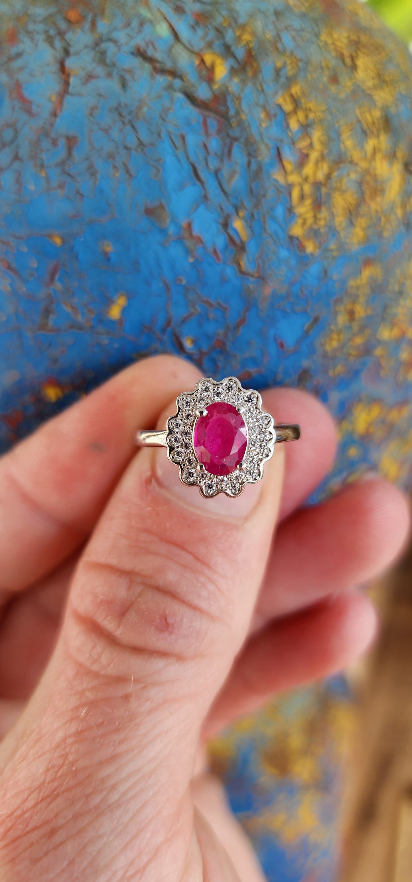 Elegant Sterling Silver, Ruby and CZ cluster/halo ring.
This lovely ring is centrally set with a Oval cut Ruby which is four claw set in Sterling Silver.