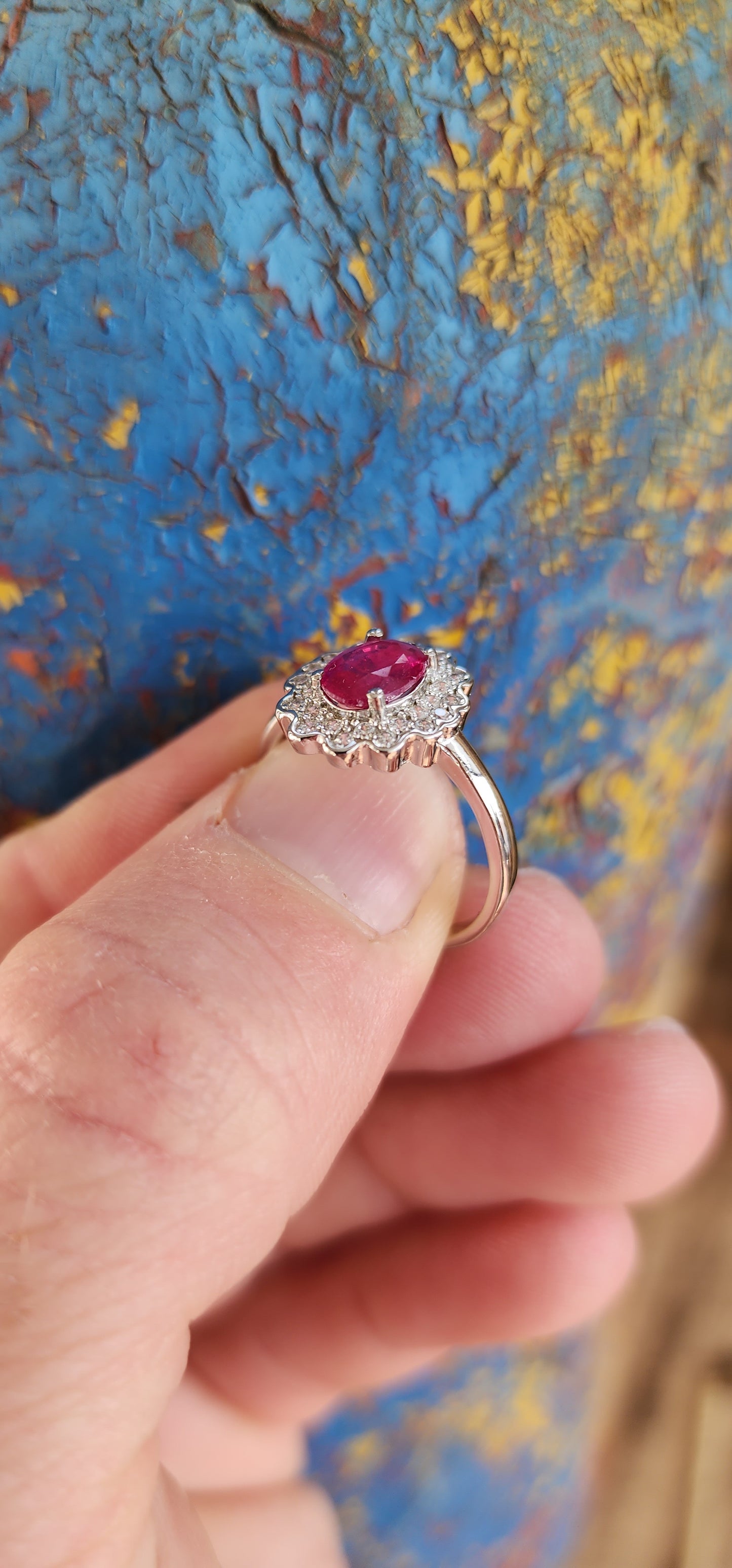 Elegant Sterling Silver, Ruby and CZ cluster/halo ring.
This lovely ring is centrally set with a Oval cut Ruby which is four claw set in Sterling Silver.