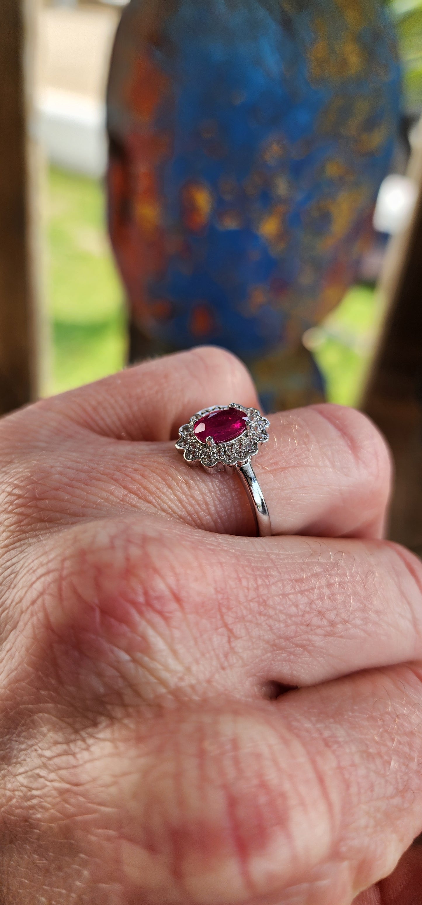 Elegant Sterling Silver, Ruby and CZ cluster/halo ring.
This lovely ring is centrally set with a Oval cut Ruby which is four claw set in Sterling Silver.