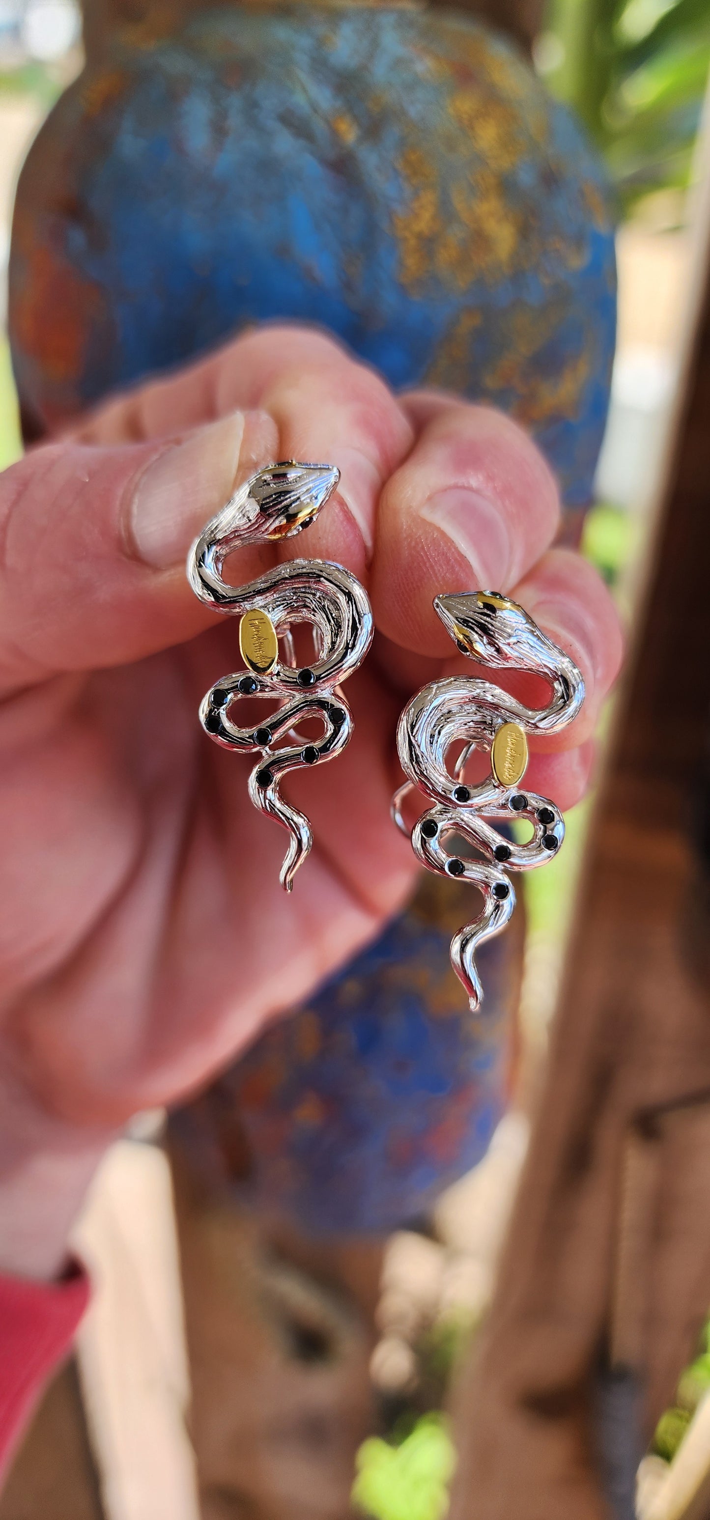 Elegantly crafted Sterling Silver coiling Serpent statement push-in earrings. The Serpents have a textured appearance on their bodies. Black flush set Spinel Gemstones highlight the eyes and body of the Serpents.