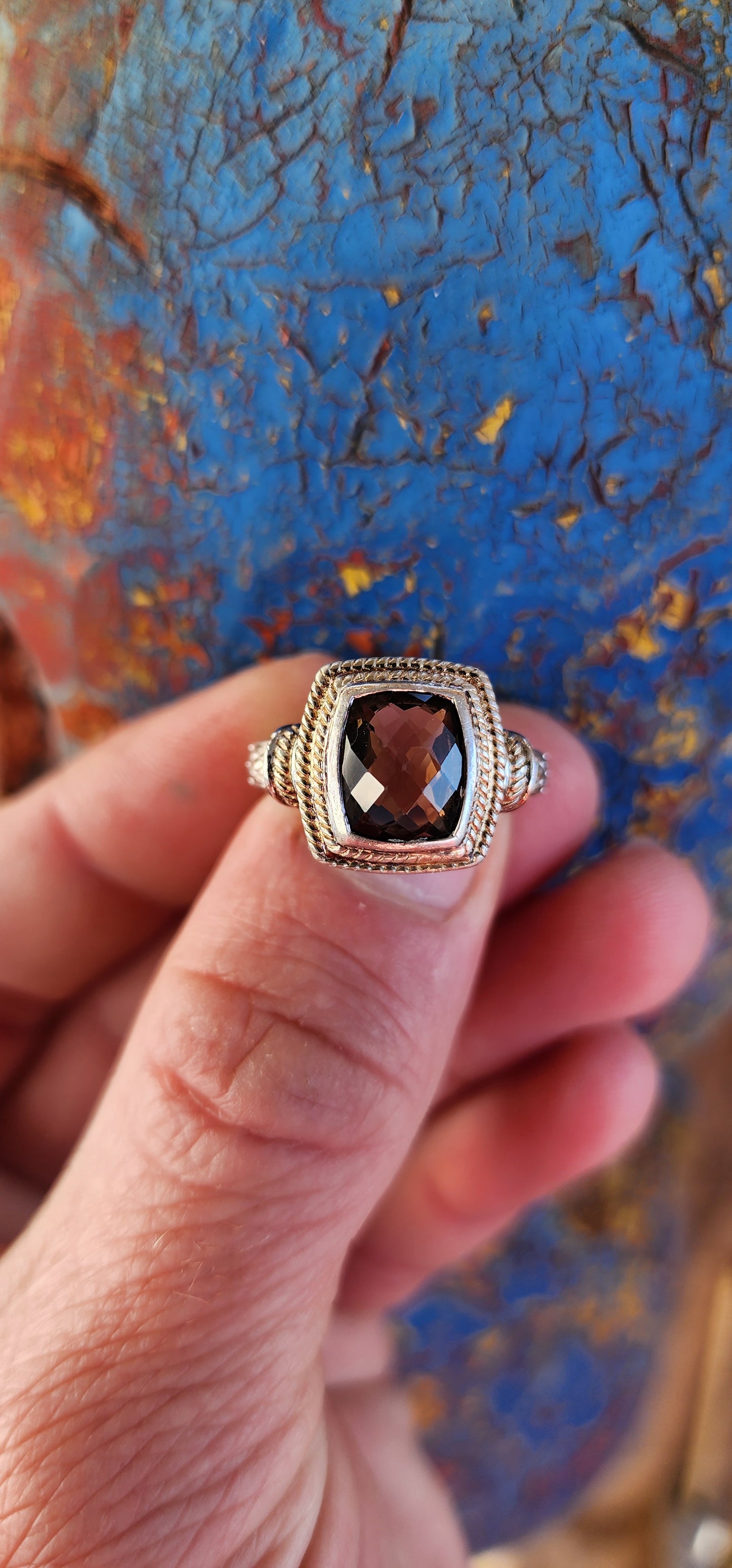 A beautifully made Designer Sterling Silver ring showcasing a Checkerboard faceted Rectangular Cushion cut Smoky Quartz Gemstone, bezel/tube set and positioned in the center.
The Smoky Quartz is encircled by a double cable halo.