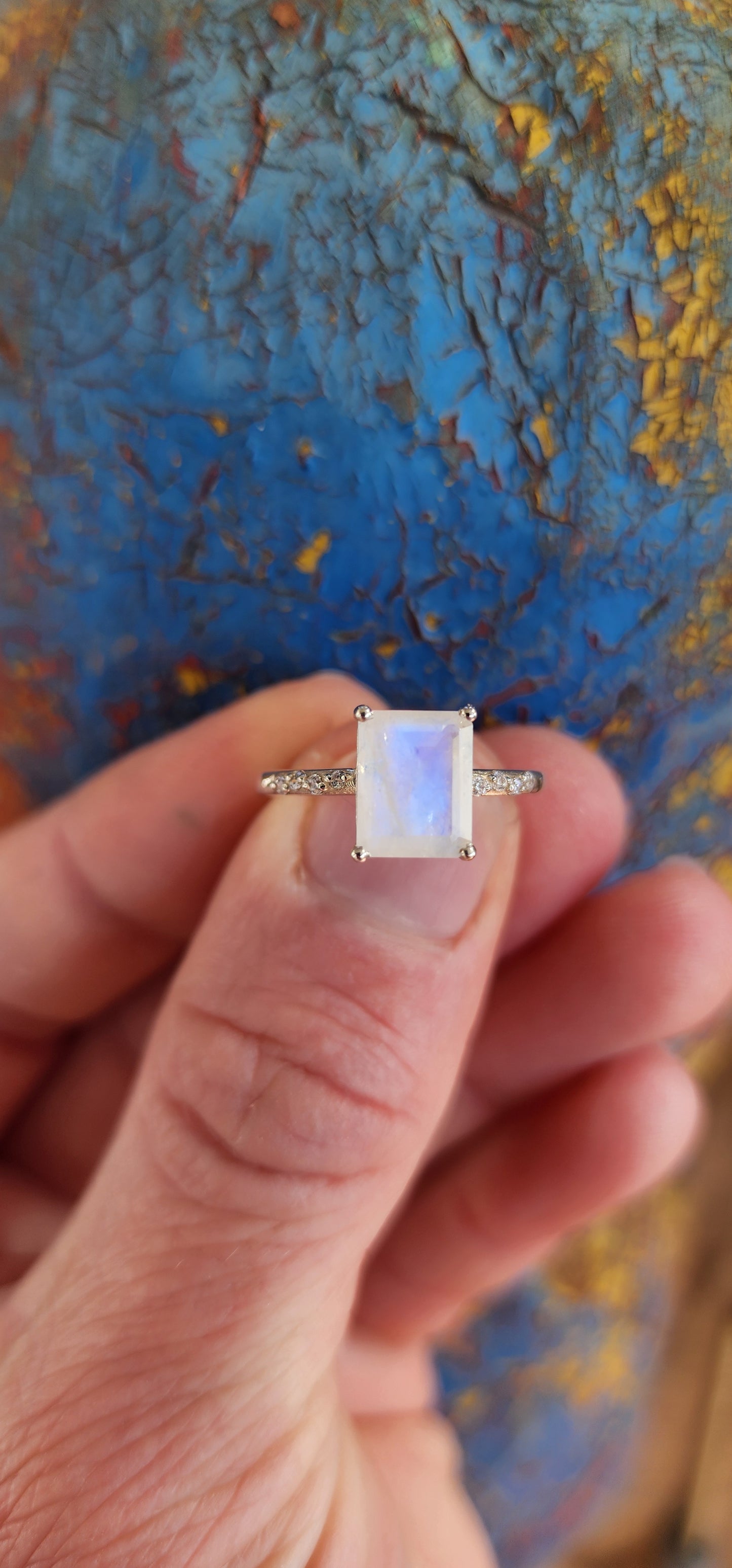 No matter your attire, this Sterling Silver Solitaire style ring guarantees youll shine in the spotlight. Adorned with a Emerald Cut Moonstone in a prong Setting and small Round cut CZ Gemstones gracing its shoulders.