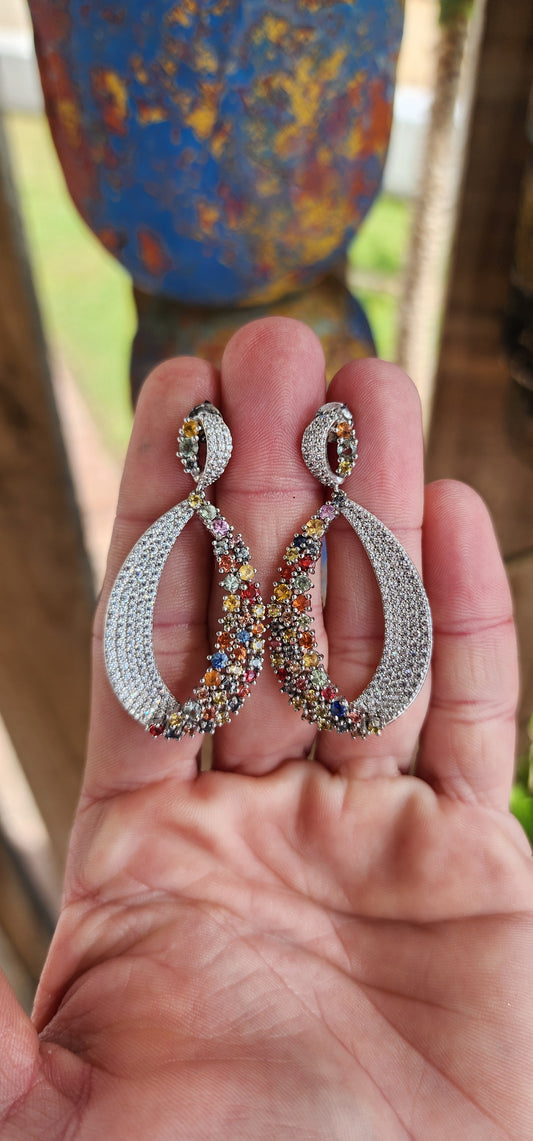 Unique and oversized statement push-in drop earrings crafted in Sterling Silver. Pear shaped drops adorned with prong set Multi-color Sapphire Gemstones on one side and Pave set CZ Gemstones on the other side.