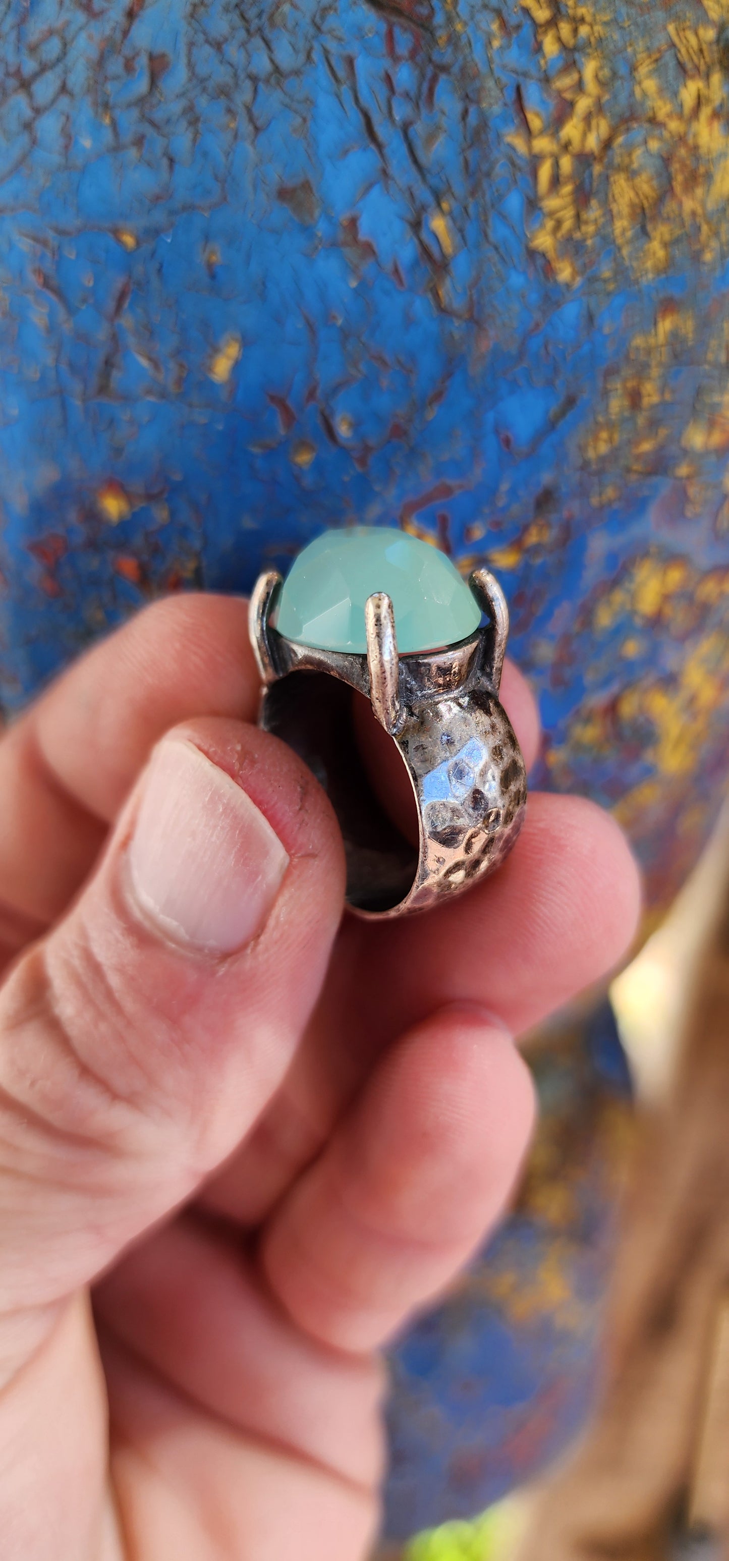 Glorious studio/artisan made statement ring.Crafted in Sterling Silver, the Black patinated band featuring a hammered/textured pattern , prong set in the centre is lovely Oval faceted cut Aqua Chalcedony Gemstone.