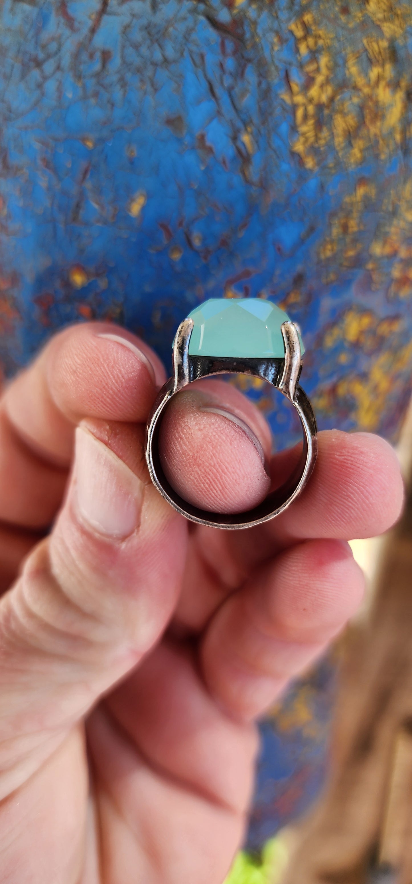 Glorious studio/artisan made statement ring.Crafted in Sterling Silver, the Black patinated band featuring a hammered/textured pattern , prong set in the centre is lovely Oval faceted cut Aqua Chalcedony Gemstone.