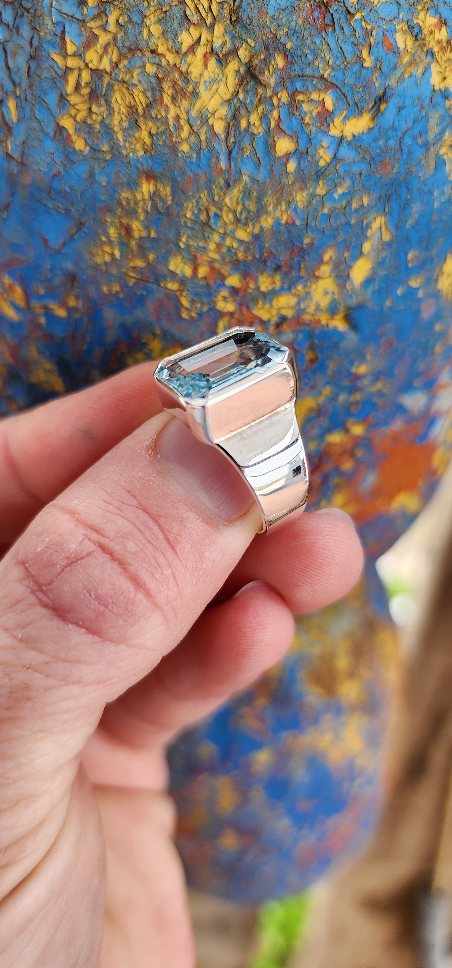 Stunning handcrafted unisex Sterling Silver ring showcases a gorgeous, large Emerald cut Sky Blue Topaz Gemstone set in a bezel/tube setting, with a tapered Silver band.Such an incredibly stunning ring!