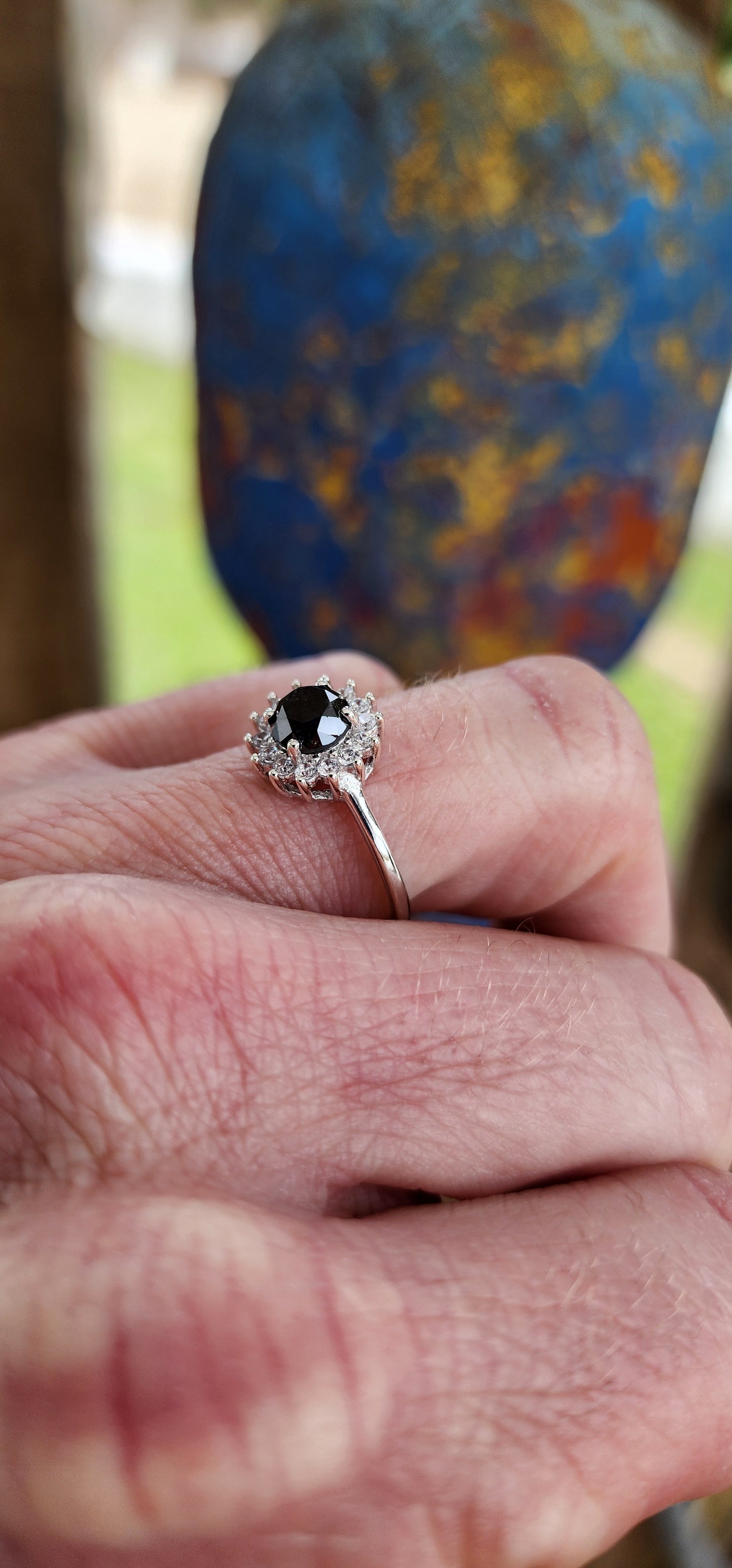 Elegant Solitaire/halo ring showcasing a stunning Round Black Diamond haloed by sparkling White CZ Gemstones.