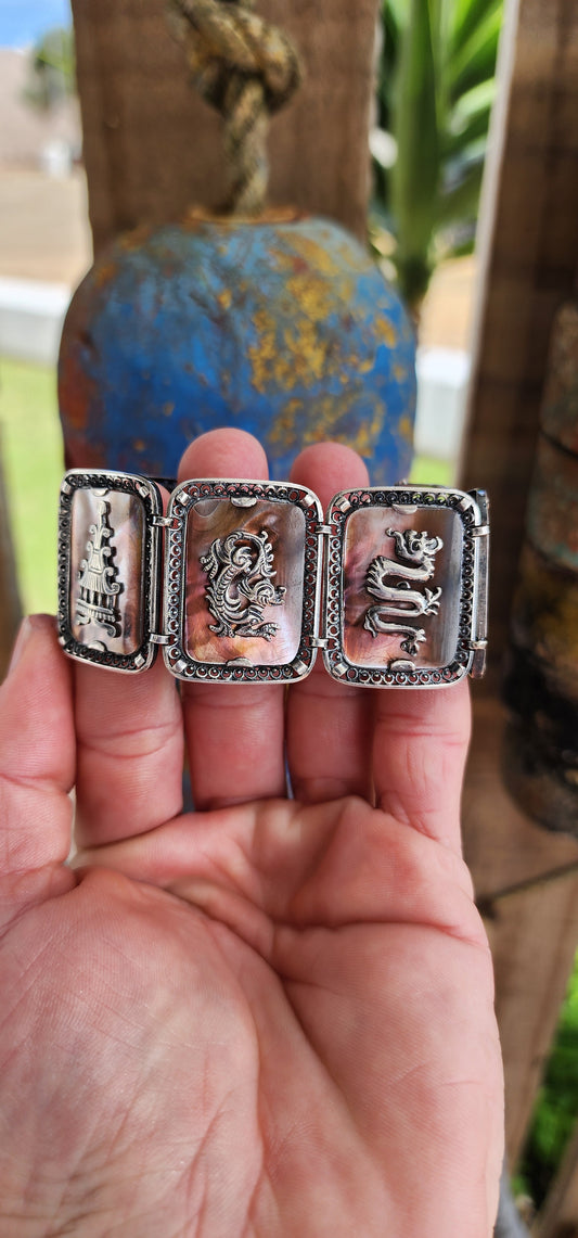 Antique Art Deco era circa 1920/30's 800 silver and Abelone Shell Oriental inspired panel bracelet.
Seven Rectangular Abelone Shell panels are each secured with prong settings in intricate filigree frames and are decorated with Oriental motifs.