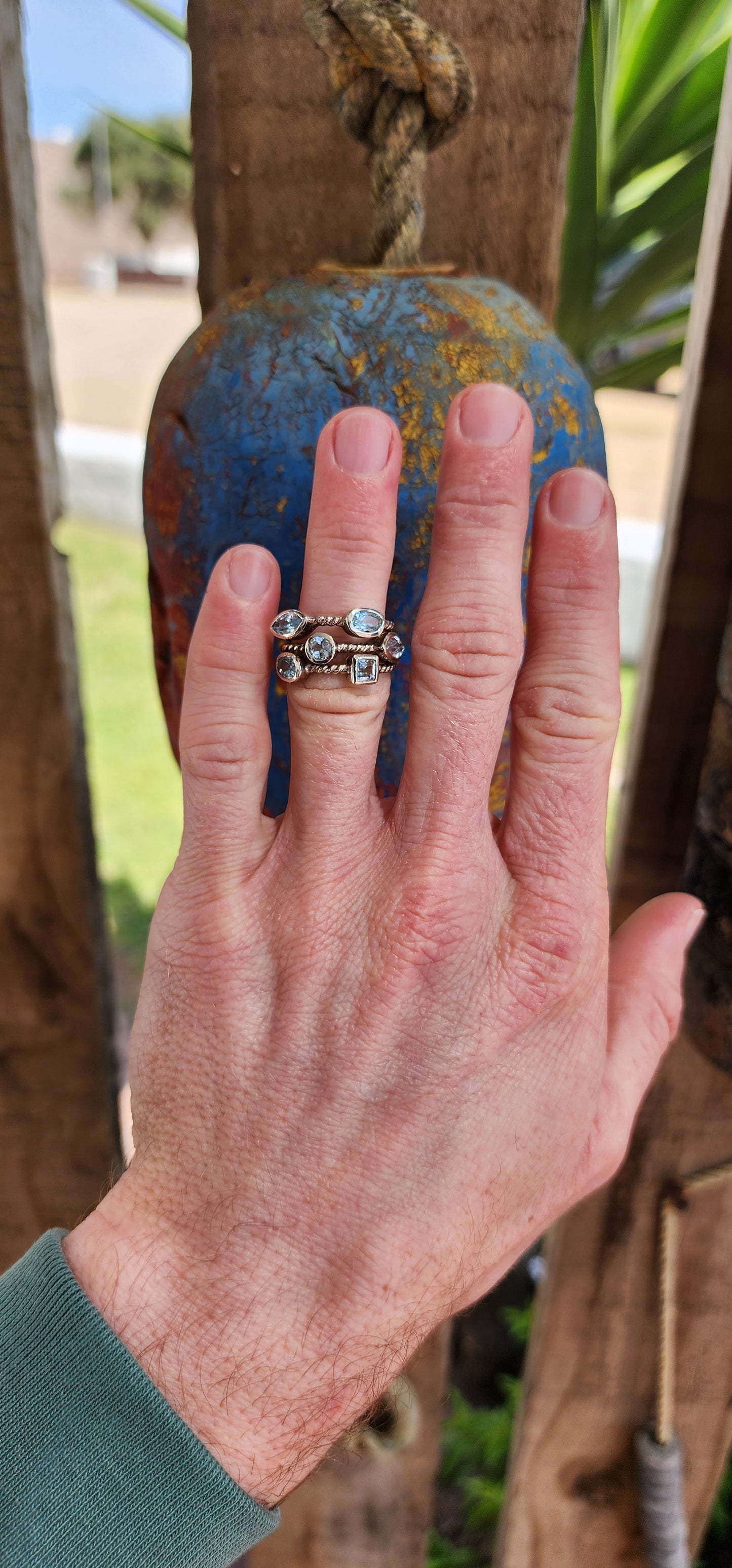 This unique Sterling Silver cluster ring features a Rope pattern on three bands and is adorned with Sky Blue Topaz Gemstones in various shapes and sizes.
The Topaz Gemstones being bezel/tube set.