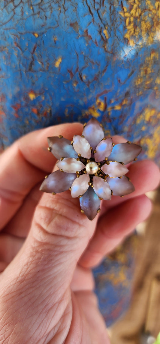 This Vintage brooch, likely from the 1950s, has a beautiful floral design. The centerpiece is a faux pearl, surrounded by two layers of Marquise-cut Sappharine glass stones.