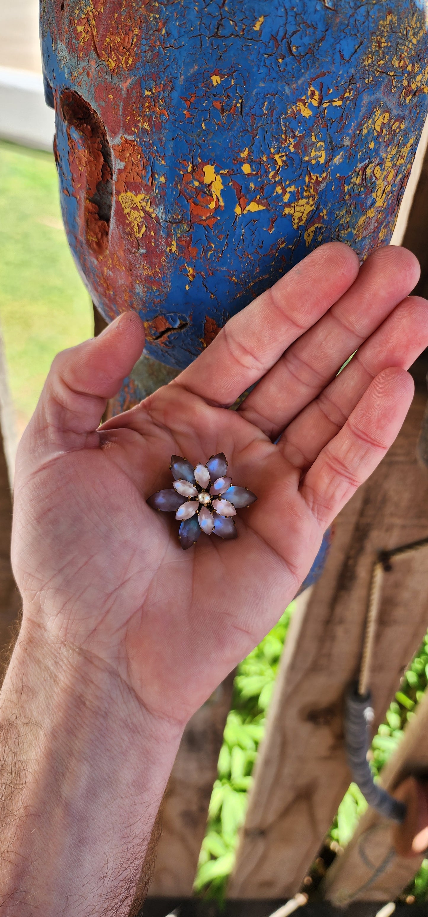 This Vintage brooch, likely from the 1950s, has a beautiful floral design. The centerpiece is a faux pearl, surrounded by two layers of Marquise-cut Sappharine glass stones.