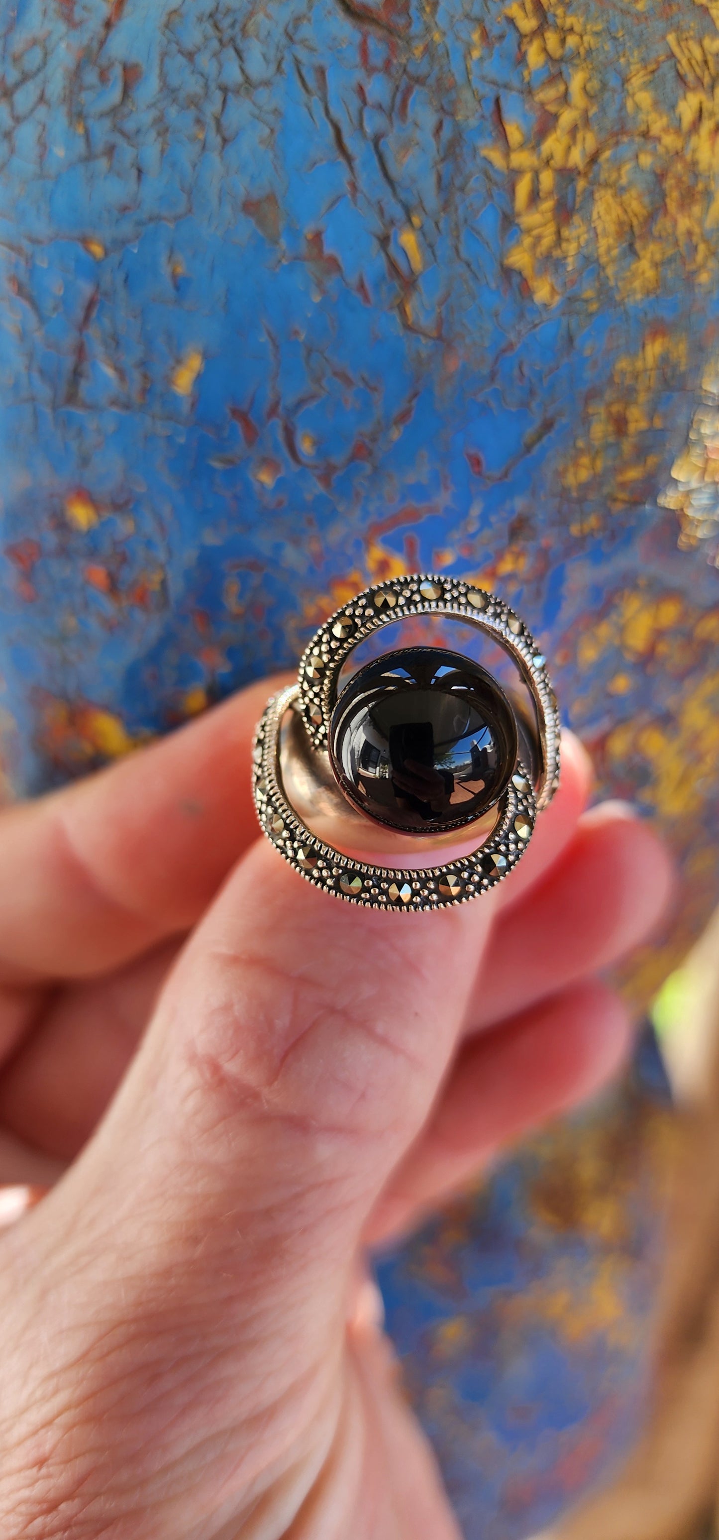 This chunky dress ring is a beautiful, Art Deco-inspired piece crafted in sterling silver. It features a prominent, spherical onyx stone at its center, often referred to as a "floating orb" due to the way it is set slightly elevated above the band.