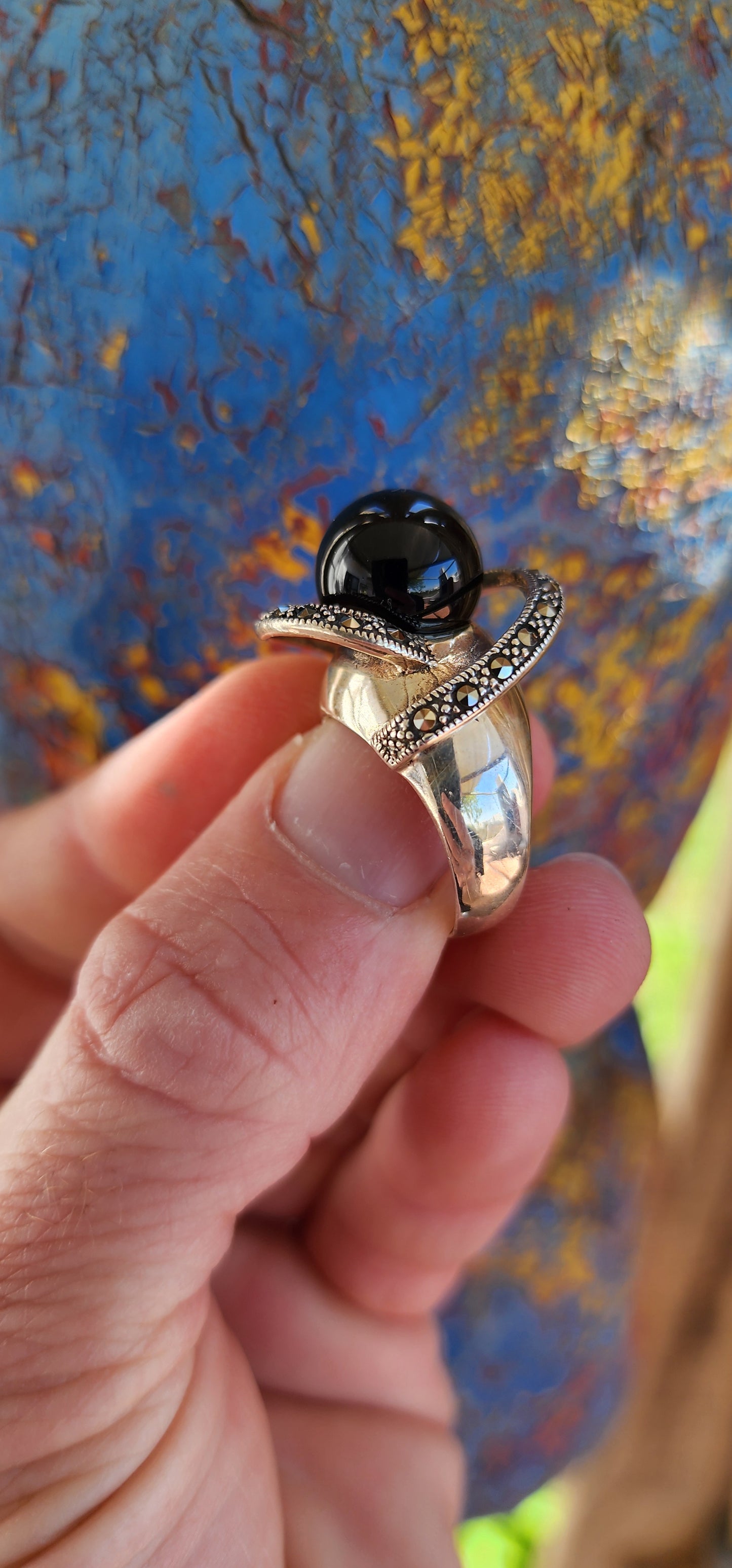 This chunky dress ring is a beautiful, Art Deco-inspired piece crafted in sterling silver. It features a prominent, spherical onyx stone at its center, often referred to as a "floating orb" due to the way it is set slightly elevated above the band.