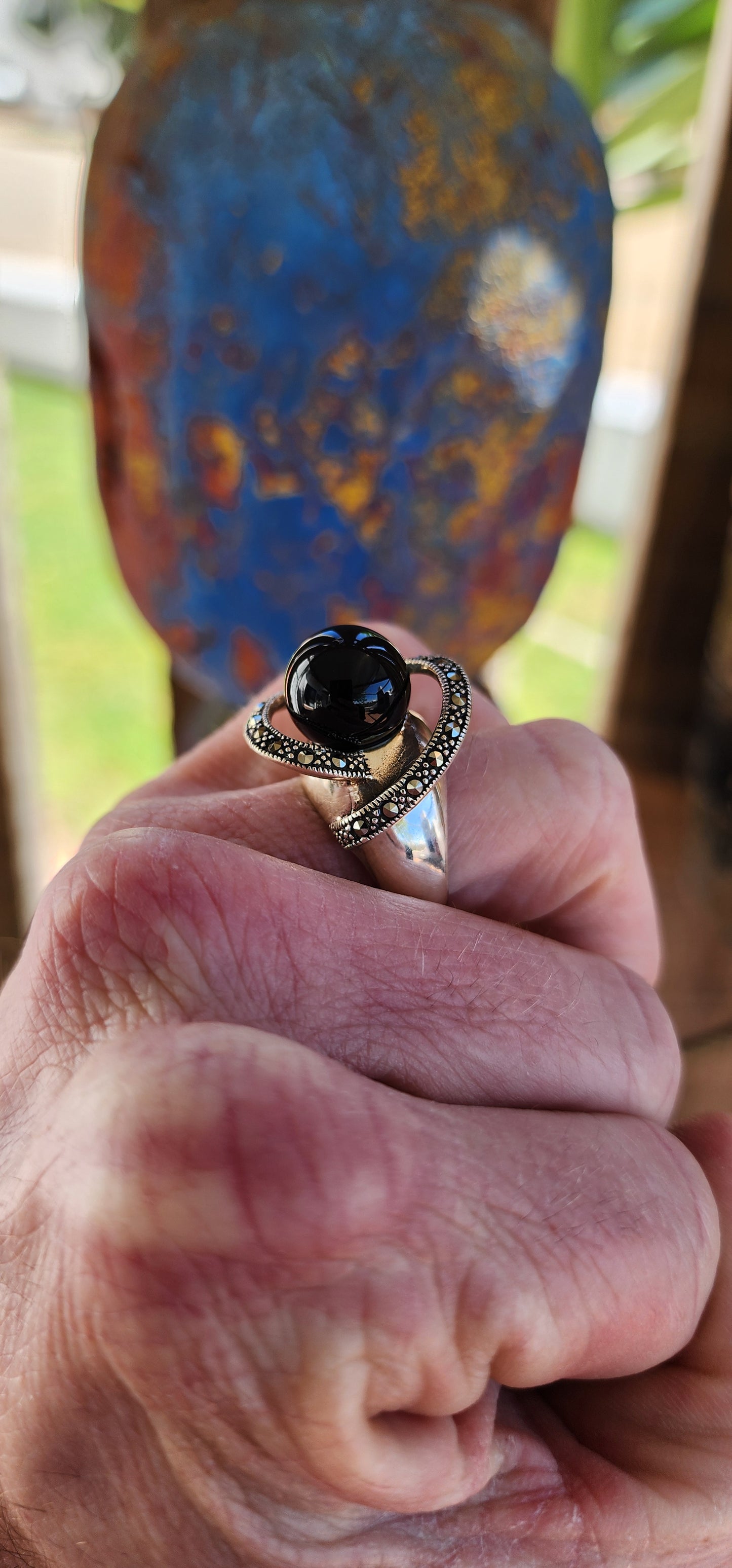 This chunky dress ring is a beautiful, Art Deco-inspired piece crafted in sterling silver. It features a prominent, spherical onyx stone at its center, often referred to as a "floating orb" due to the way it is set slightly elevated above the band.