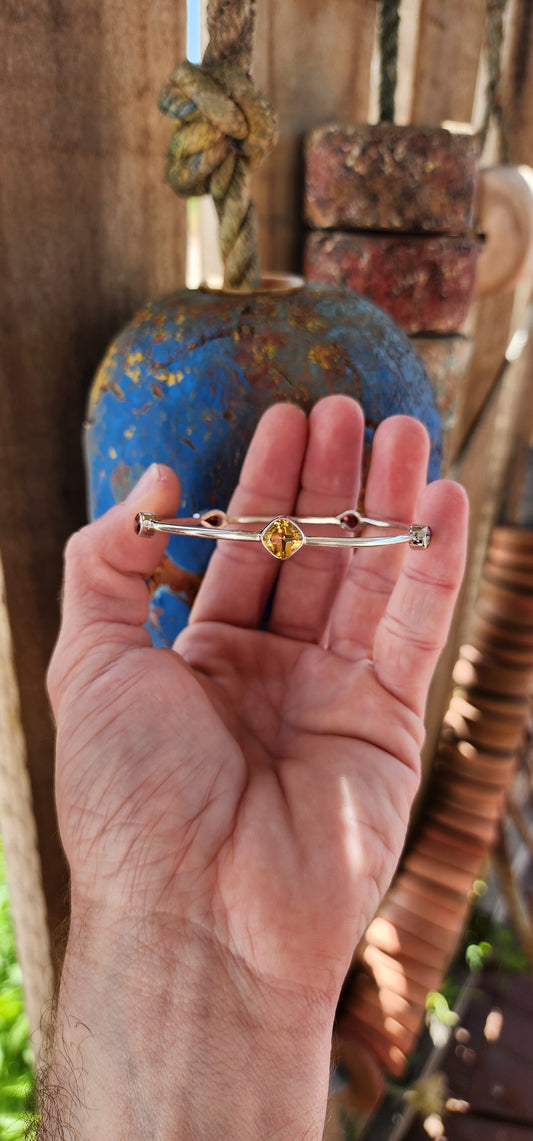 This sterling silver bangle embodies a refined balance of elegance and modern design, showcasing a harmonious arrangement of citrine and garnet gemstones.