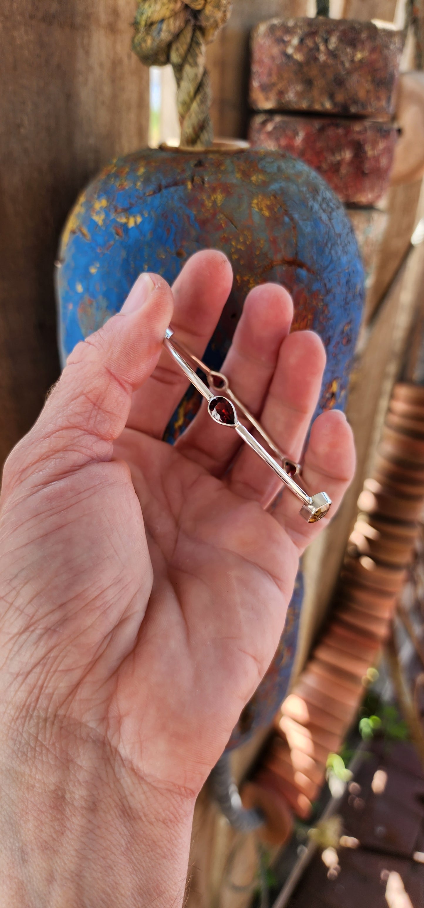 This sterling silver bangle embodies a refined balance of elegance and modern design, showcasing a harmonious arrangement of citrine and garnet gemstones.