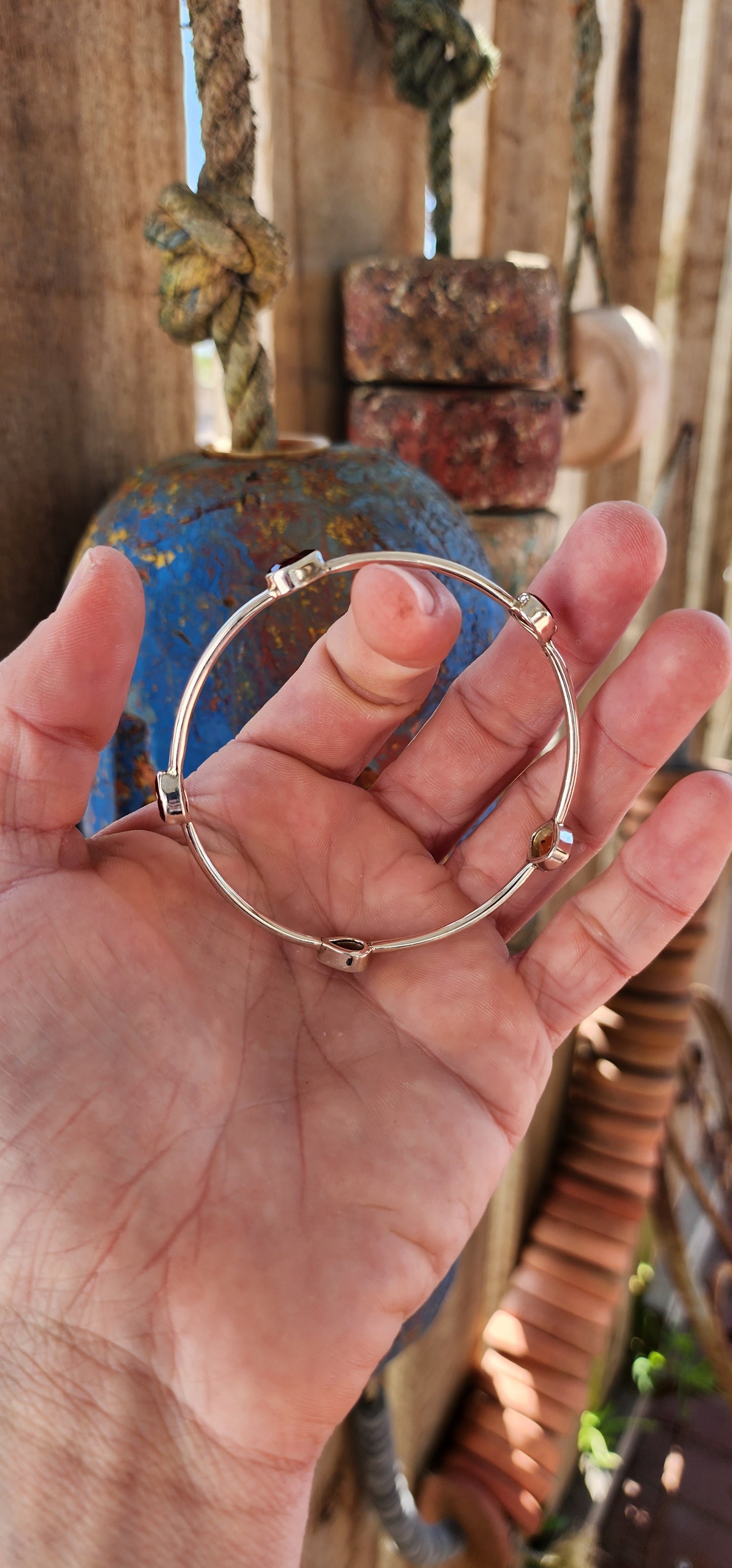 This sterling silver bangle embodies a refined balance of elegance and modern design, showcasing a harmonious arrangement of citrine and garnet gemstones.