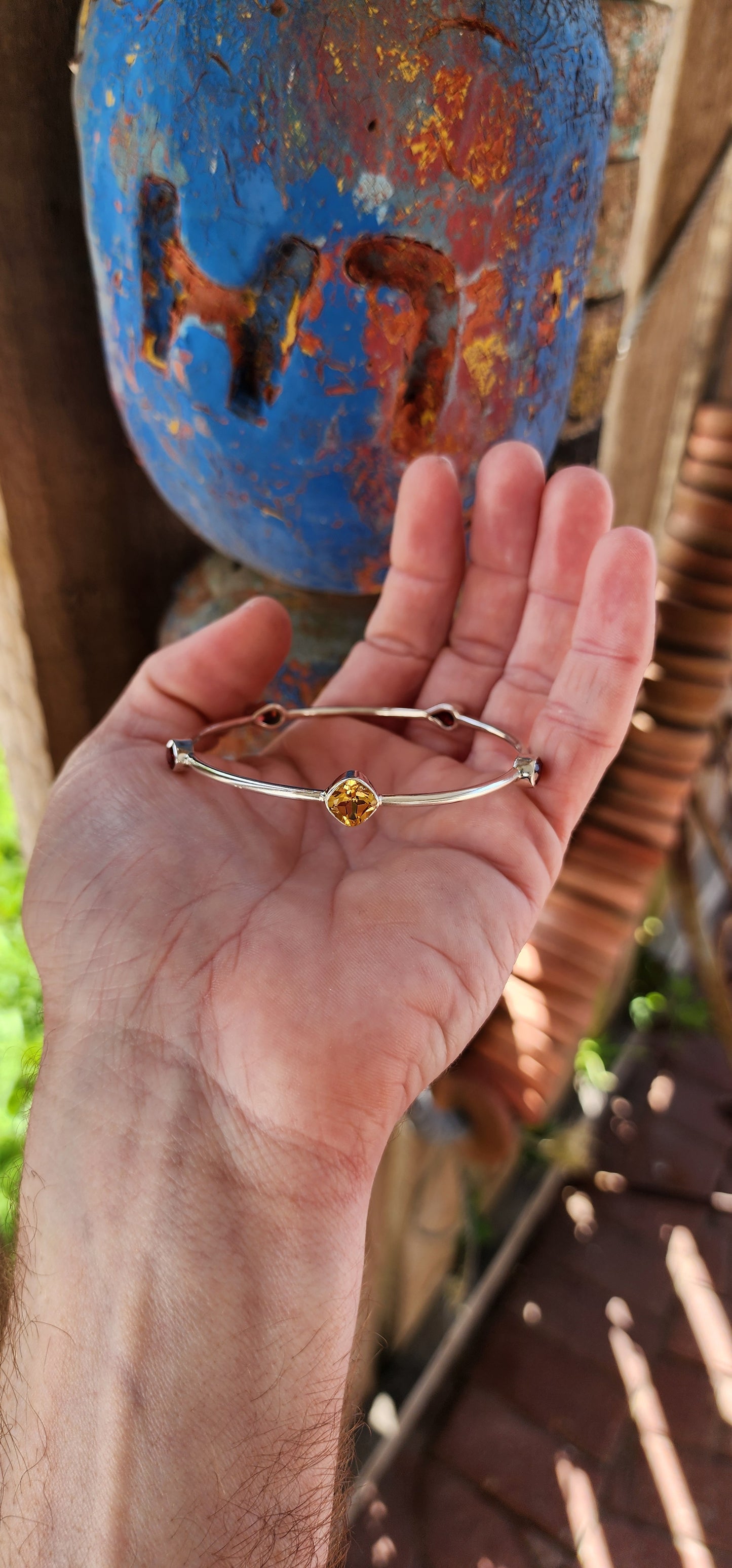 This sterling silver bangle embodies a refined balance of elegance and modern design, showcasing a harmonious arrangement of citrine and garnet gemstones.