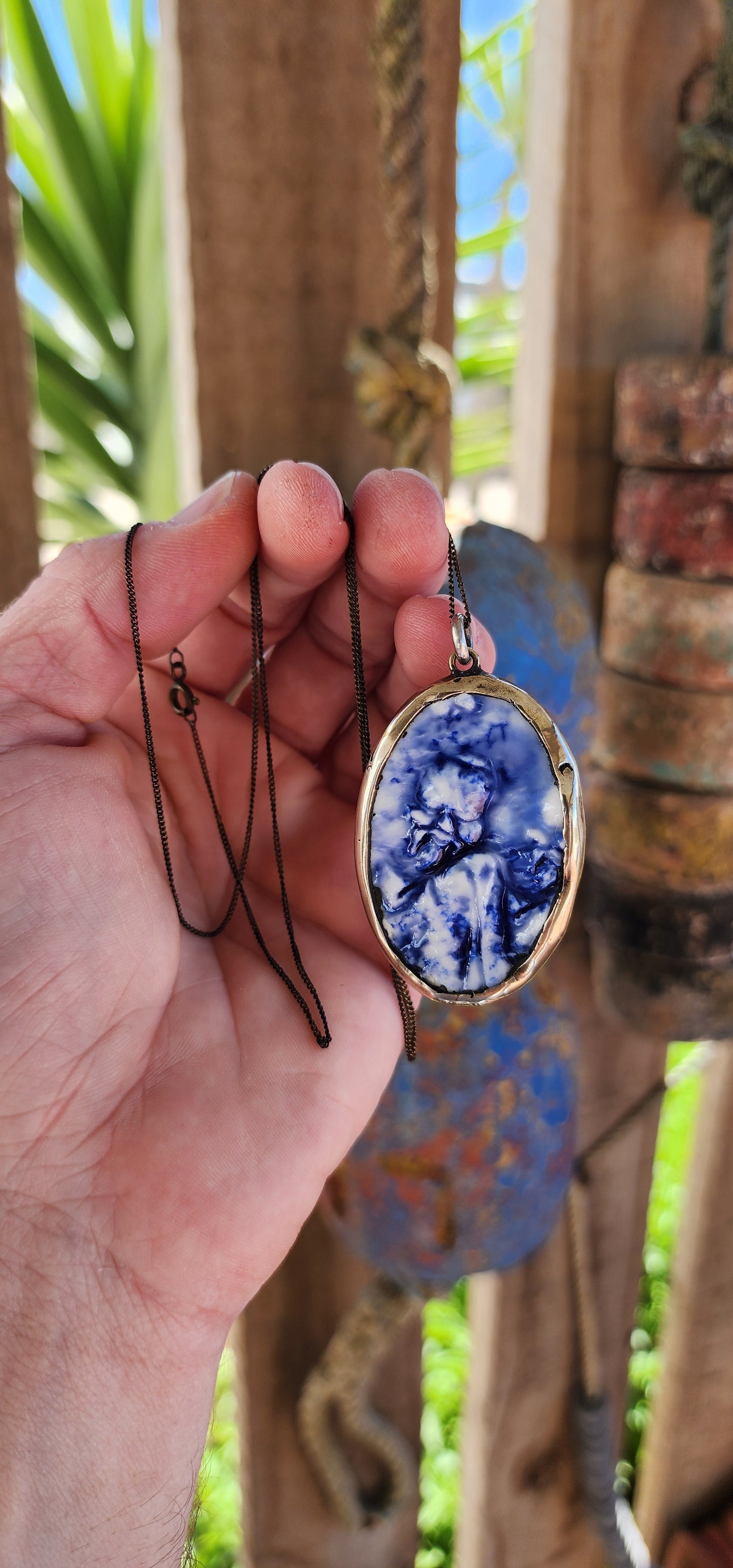 This unique Designer artisan-made pendant is a striking blend of artistry and cultural homage. Its oval shape frames a captivating blue glazed ceramic panel that presents an embossed depiction of an oriental figure.