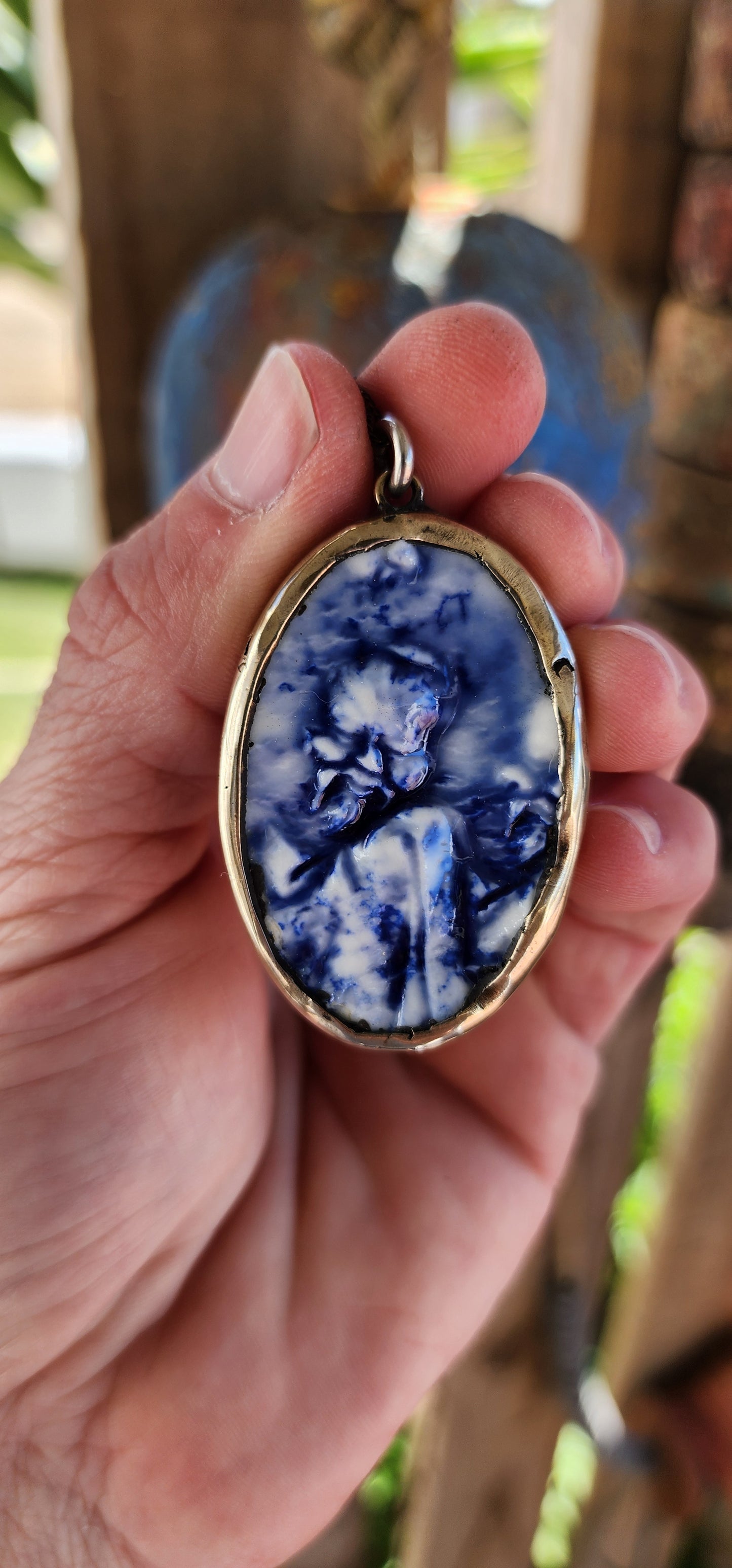 This unique Designer artisan-made pendant is a striking blend of artistry and cultural homage. Its oval shape frames a captivating blue glazed ceramic panel that presents an embossed depiction of an oriental figure.