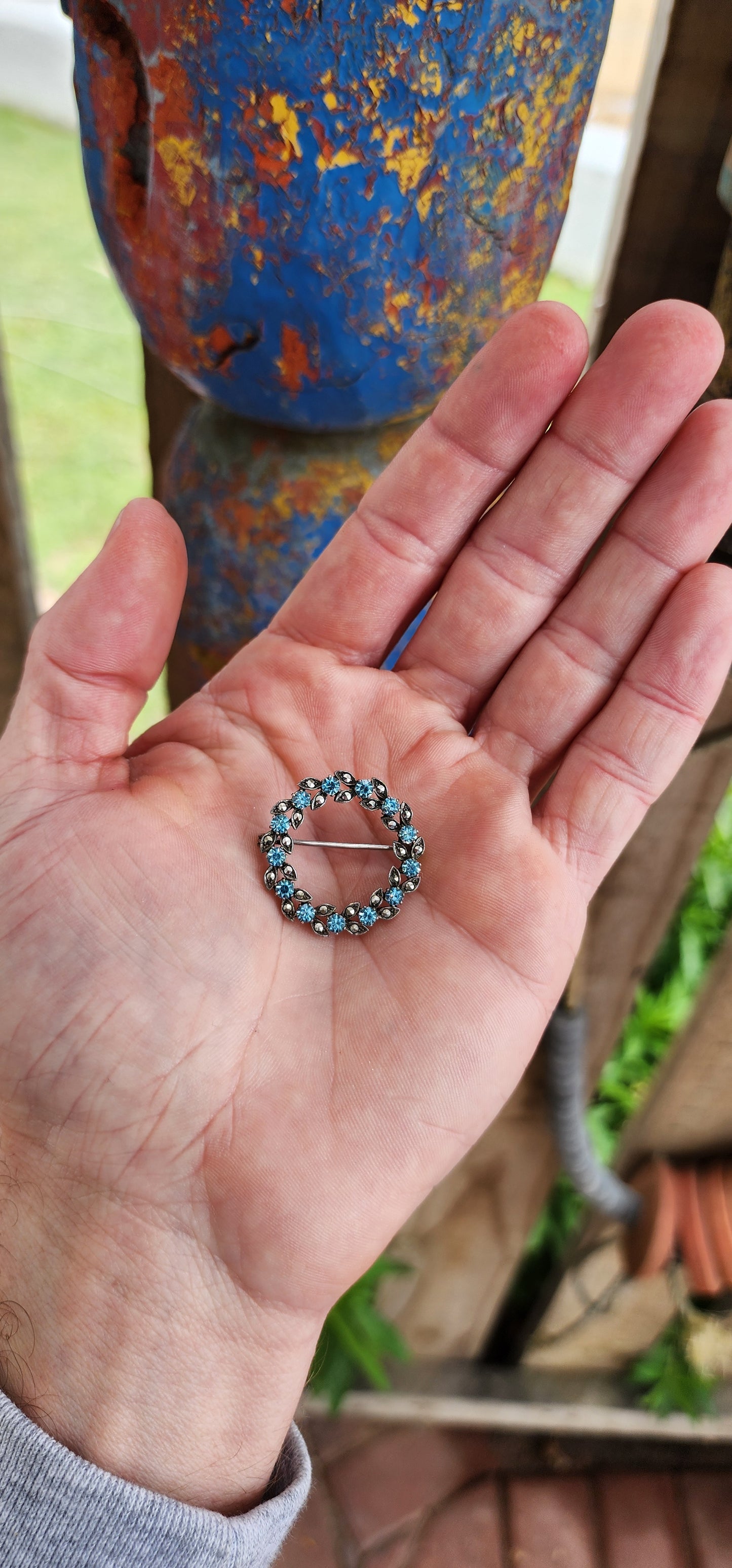 This brooch is an elegant and refined example of Art Deco jewelry, dating to the 1930s. It is crafted in sterling silver and takes the form of a delicate floral wreath.