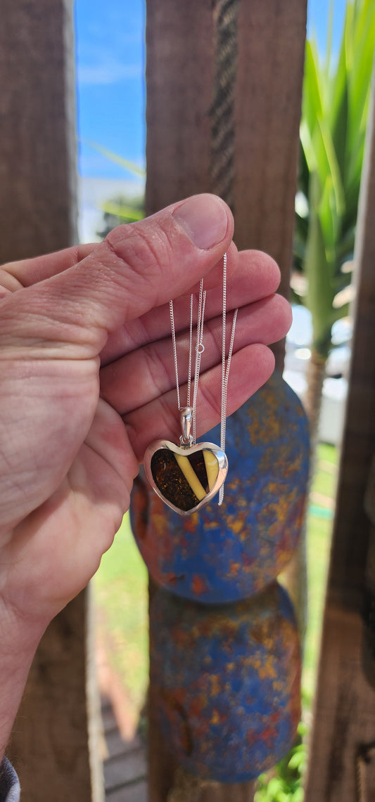 This pendant is a delightful blend of elegance and earthiness, encased in a sterling silver heart-shaped frame that exudes both warmth and sophistication. Its centerpiece is a mosaic of genuine Baltic amber, set in a harmonious pattern.