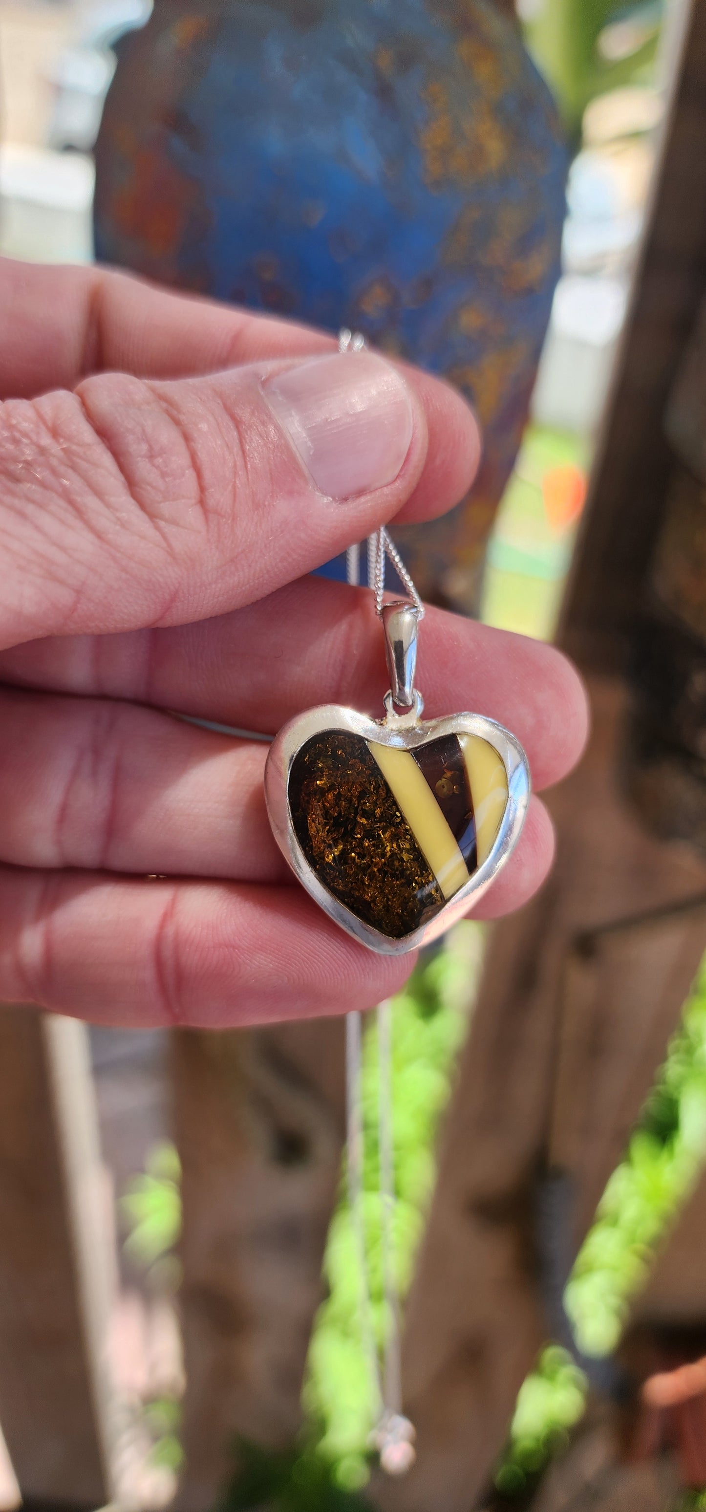 This pendant is a delightful blend of elegance and earthiness, encased in a sterling silver heart-shaped frame that exudes both warmth and sophistication. Its centerpiece is a mosaic of genuine Baltic amber, set in a harmonious pattern.