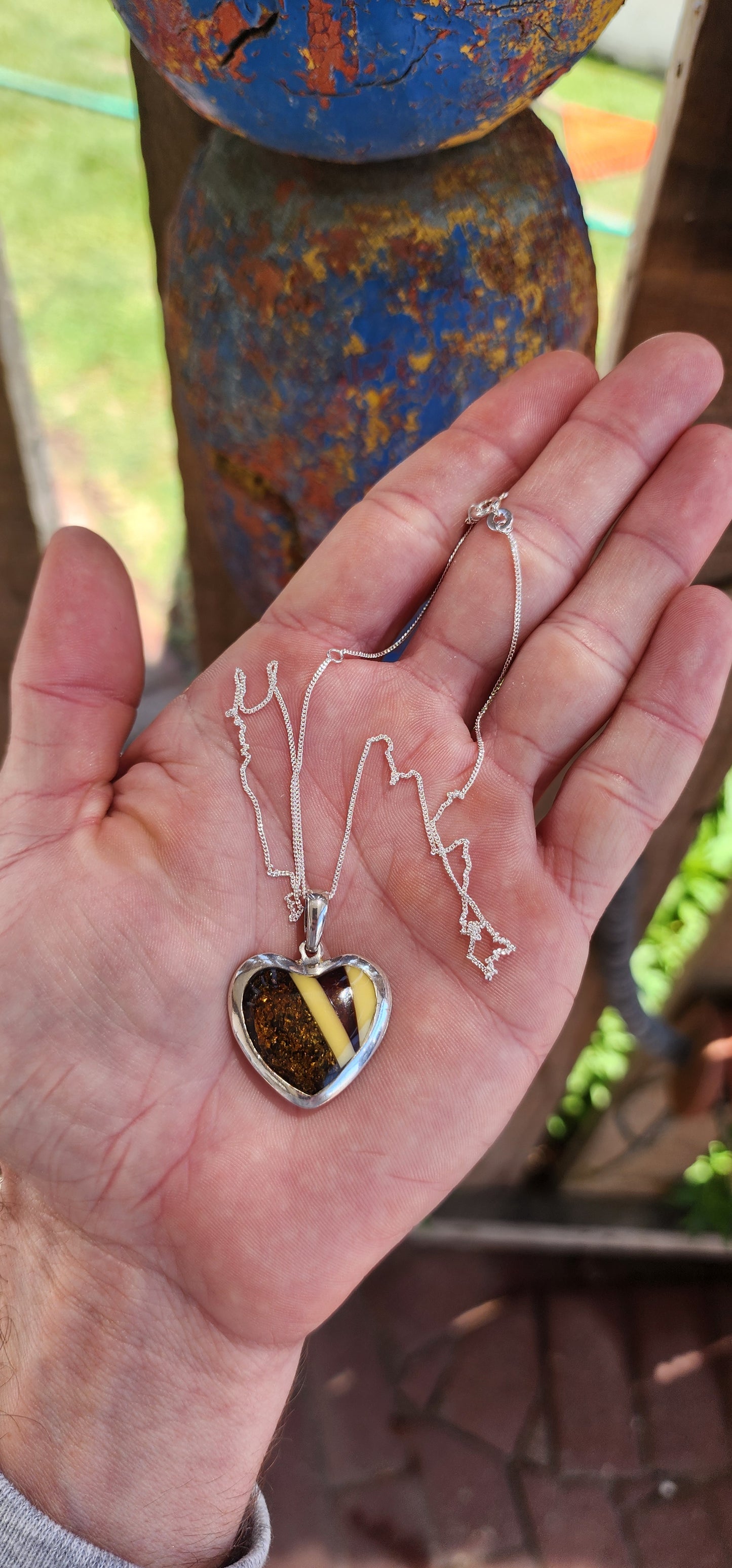 This pendant is a delightful blend of elegance and earthiness, encased in a sterling silver heart-shaped frame that exudes both warmth and sophistication. Its centerpiece is a mosaic of genuine Baltic amber, set in a harmonious pattern.