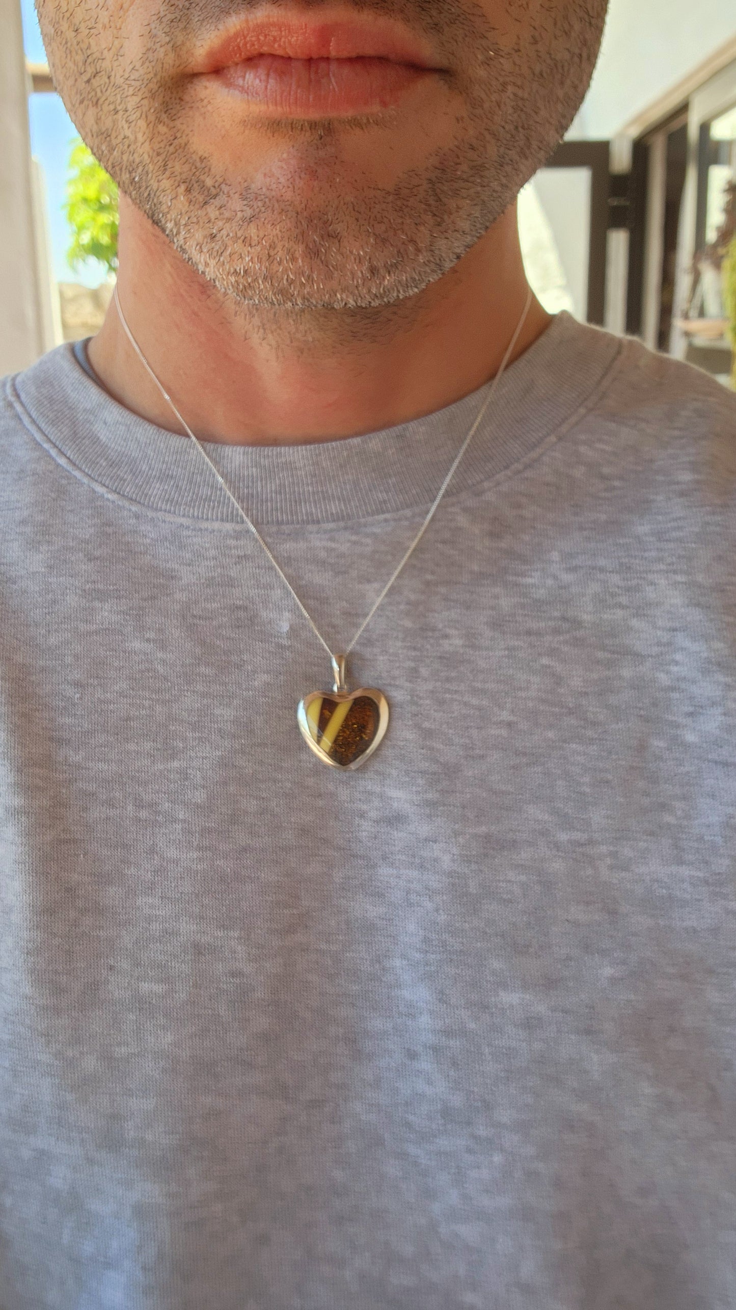 This pendant is a delightful blend of elegance and earthiness, encased in a sterling silver heart-shaped frame that exudes both warmth and sophistication. Its centerpiece is a mosaic of genuine Baltic amber, set in a harmonious pattern.