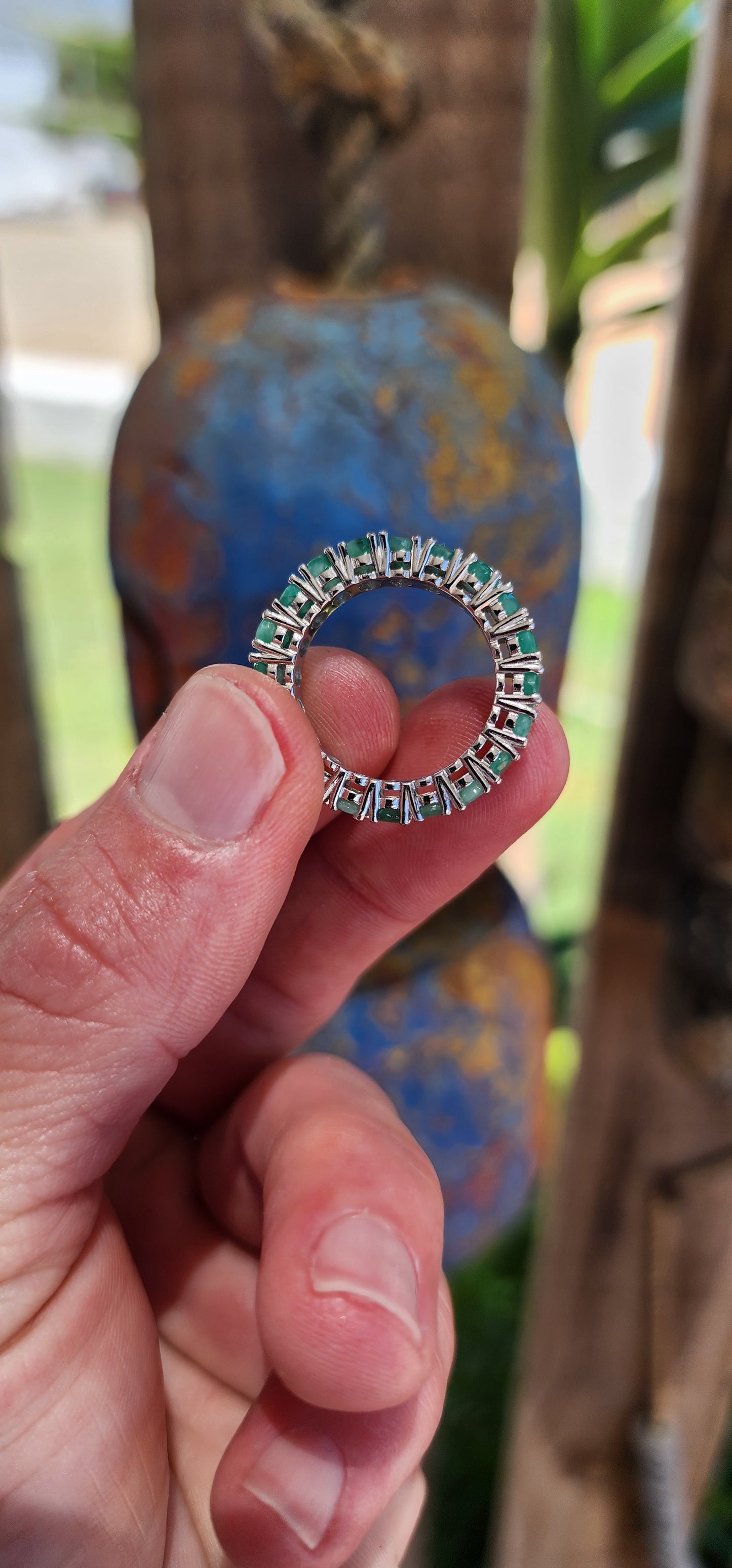 This stunning sterling silver full eternity ring is a true showstopper, set with 20 vibrant oval-cut emerald gemstones, each securely held in prong settings.