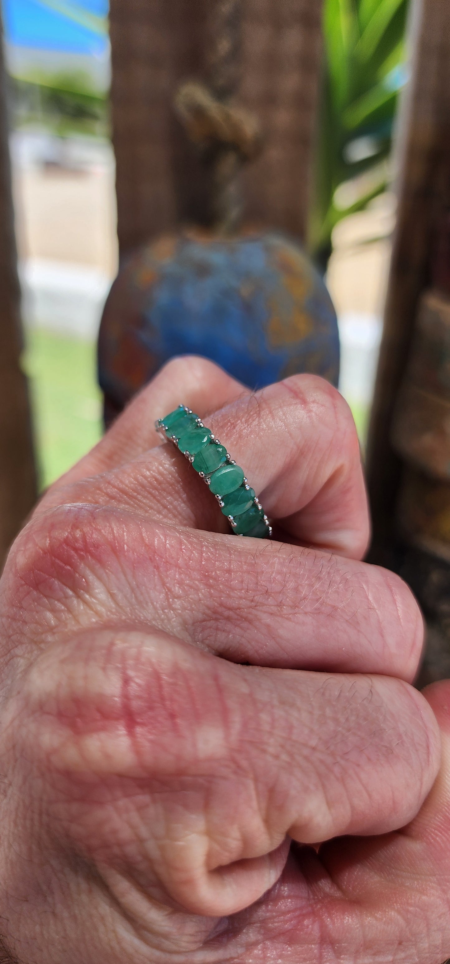 This stunning sterling silver full eternity ring is a true showstopper, set with 20 vibrant oval-cut emerald gemstones, each securely held in prong settings.