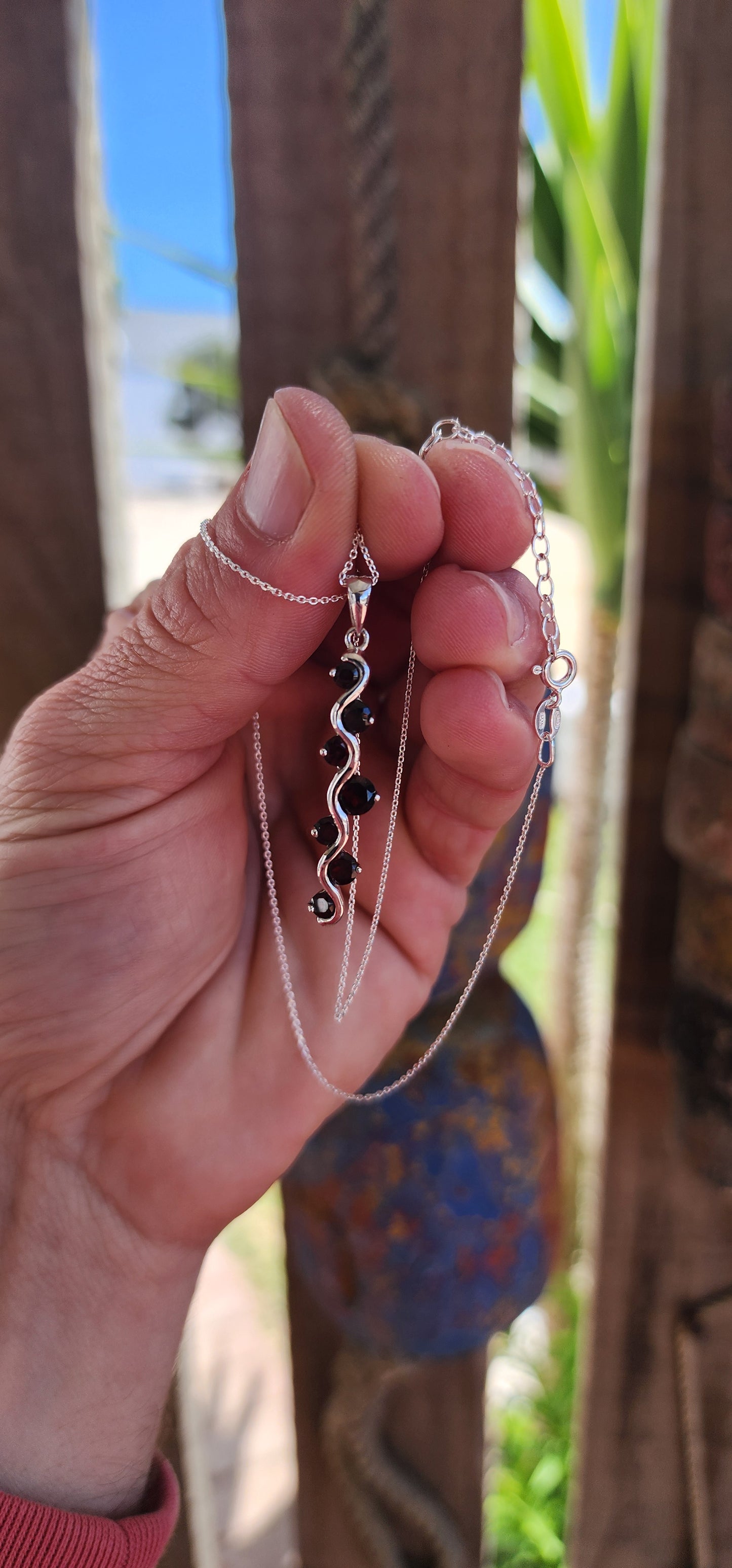 This sterling silver and garnet matching jewelry set is a testament to timeless craftsmanship and elegant design, composed of a pair of half-round push-in earrings with safety leverbacks and a gracefully matching pendant on an adjustable-length chain.