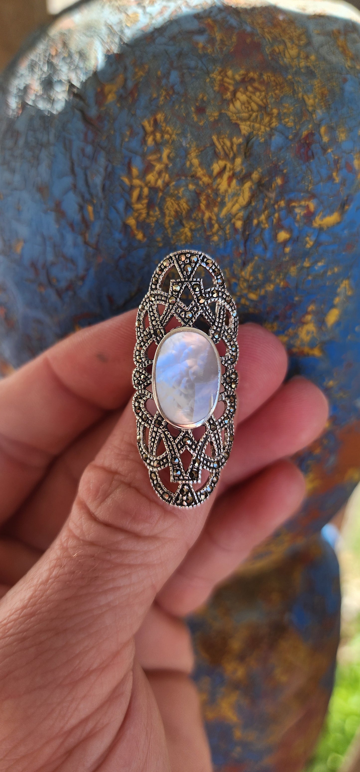 Nestled in the cradle of a sterling silver filigree lattice, this ethereal ring whispers of ancient secrets and lunar enchantments. Its centerpiece—a luminous oval cabochon of mother-of-pearl—glows like a shard of the moon, forever caught in twilight.