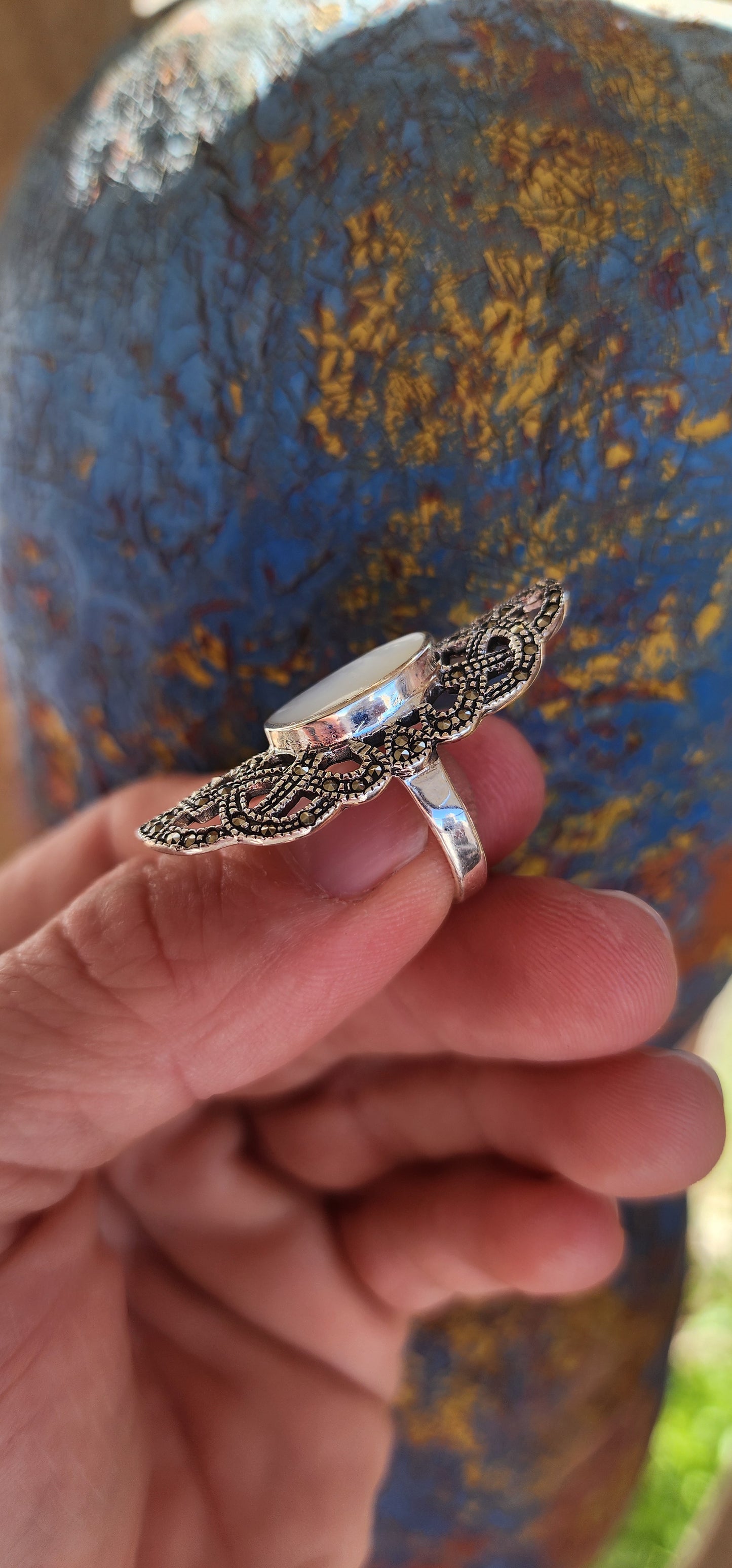 Nestled in the cradle of a sterling silver filigree lattice, this ethereal ring whispers of ancient secrets and lunar enchantments. Its centerpiece—a luminous oval cabochon of mother-of-pearl—glows like a shard of the moon, forever caught in twilight.