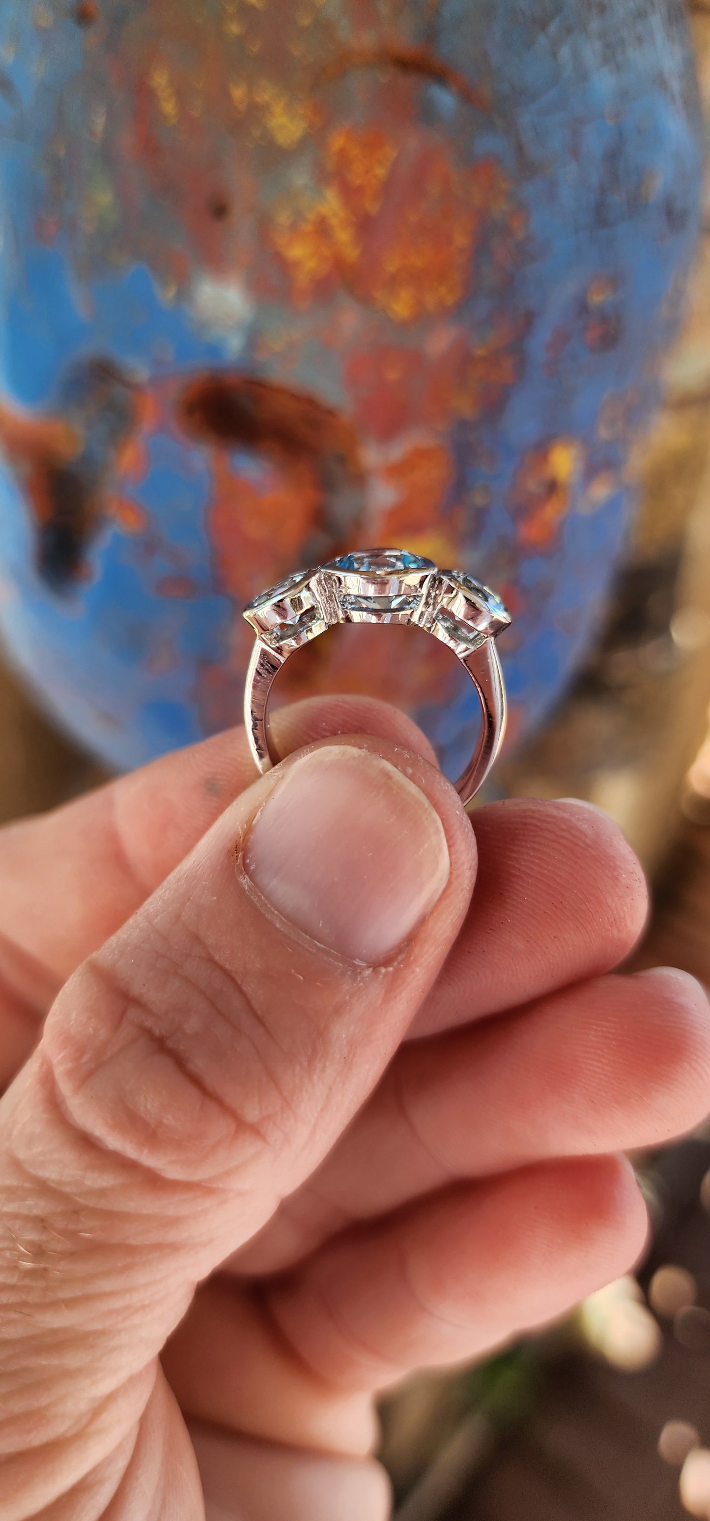 This sterling silver trilogy ring is an elegant embodiment of simplicity and beauty. Its design centers on a radiant round-cut sky blue topaz, tube-set in the middle, which exudes a serene yet mesmerizing glow reminiscent of a clear summer sky.