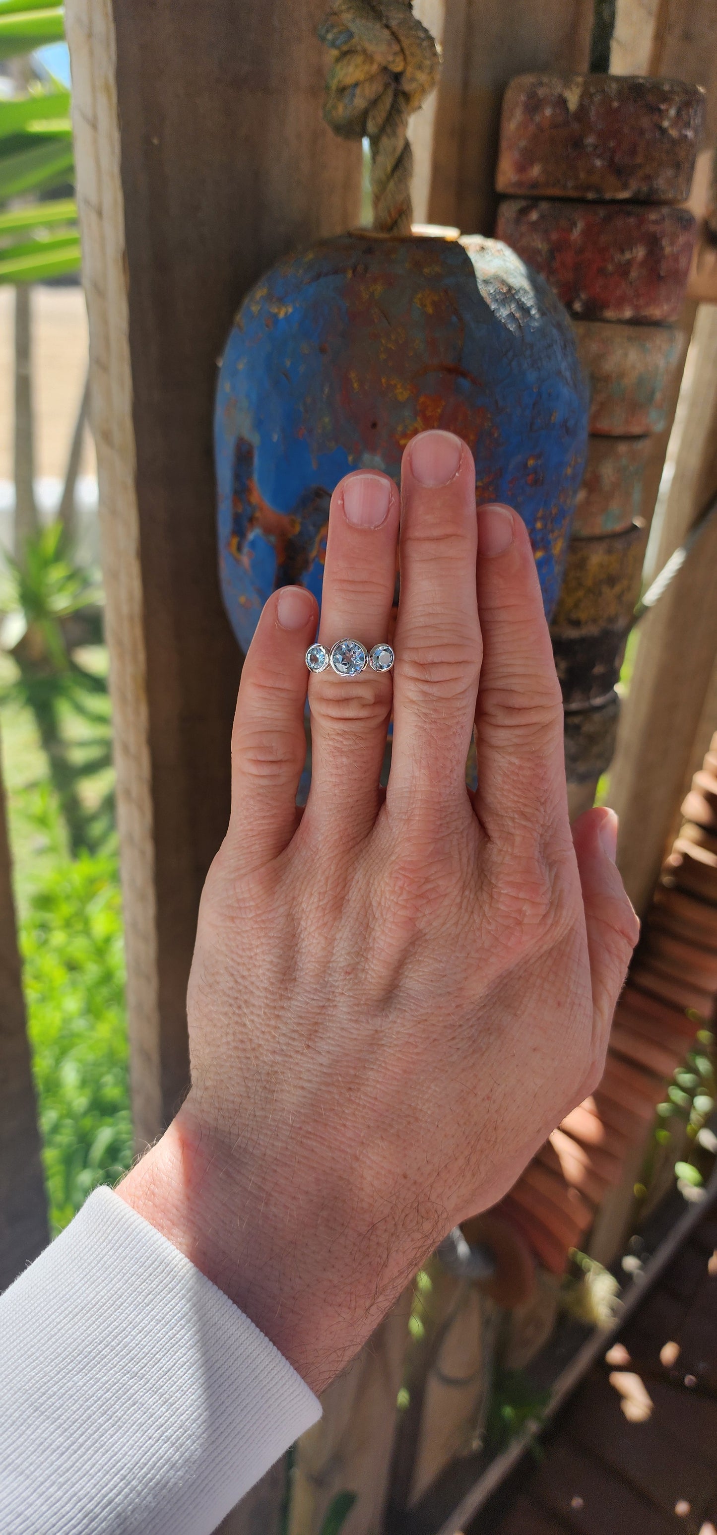 This sterling silver trilogy ring is an elegant embodiment of simplicity and beauty. Its design centers on a radiant round-cut sky blue topaz, tube-set in the middle, which exudes a serene yet mesmerizing glow reminiscent of a clear summer sky.