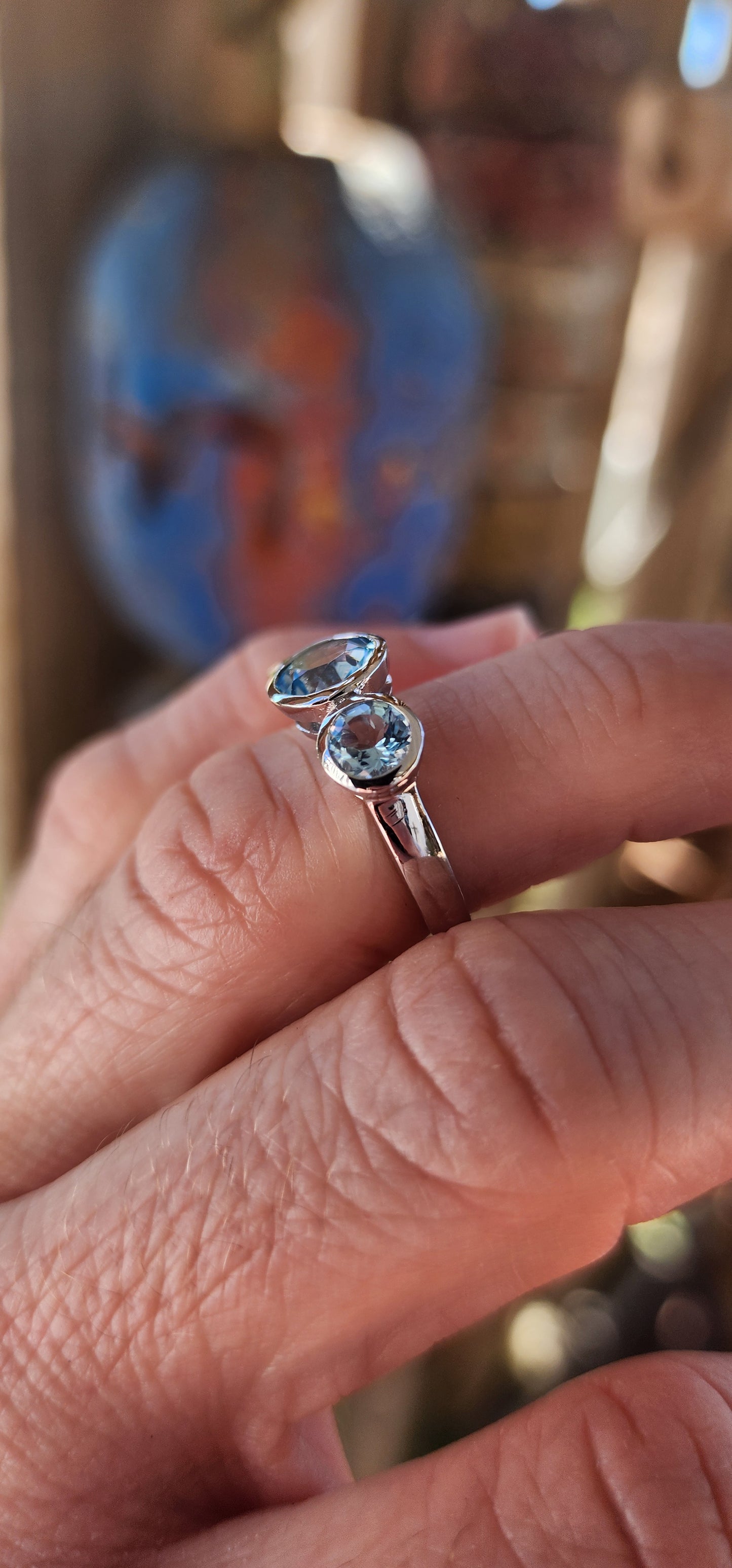 This sterling silver trilogy ring is an elegant embodiment of simplicity and beauty. Its design centers on a radiant round-cut sky blue topaz, tube-set in the middle, which exudes a serene yet mesmerizing glow reminiscent of a clear summer sky.