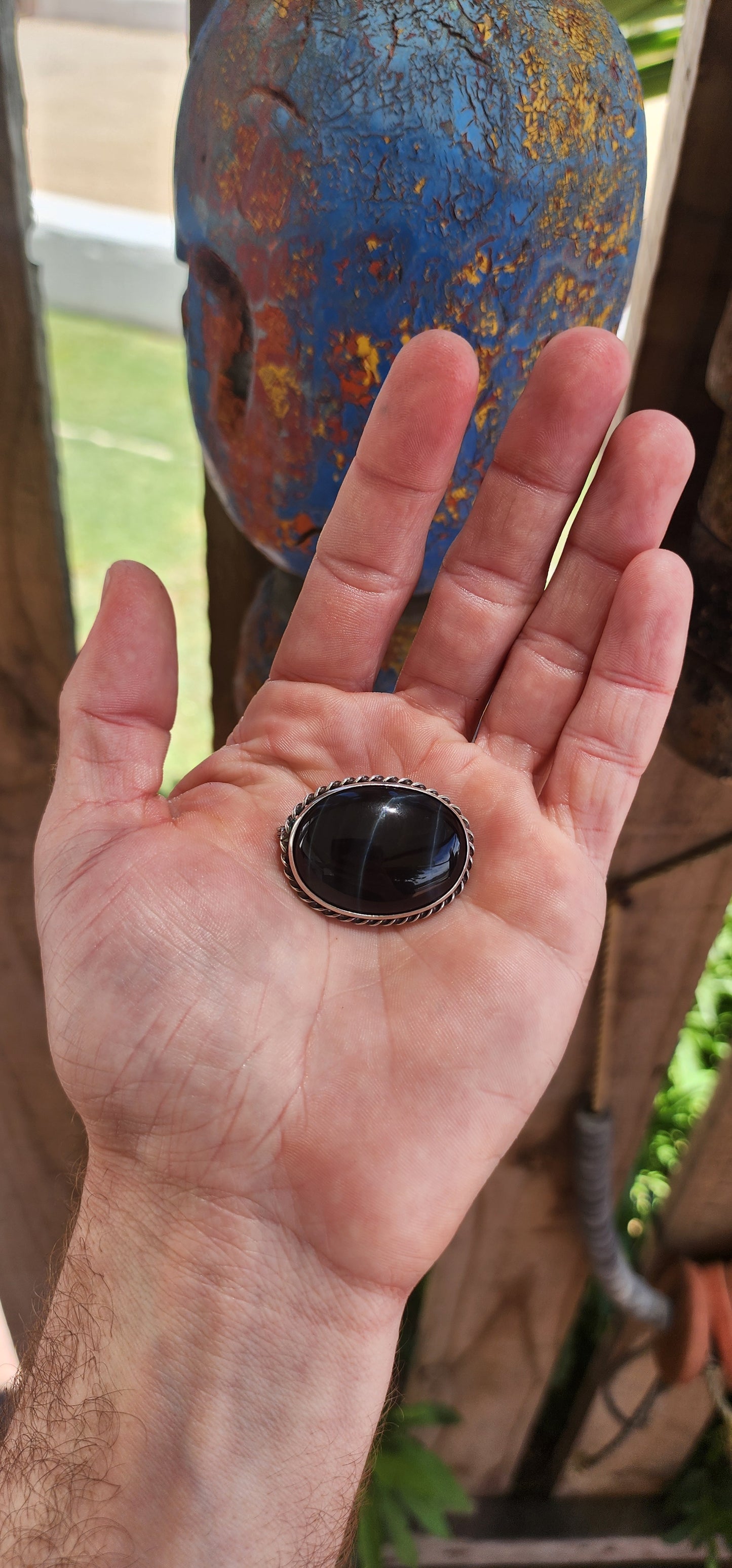 This is a vintage sterling silver oval-shaped brooch featuring a central cabochon of black tiger’s eye. The brooch's sleek and understated design highlights the natural beauty of the stone and the craftsmanship of the silver.