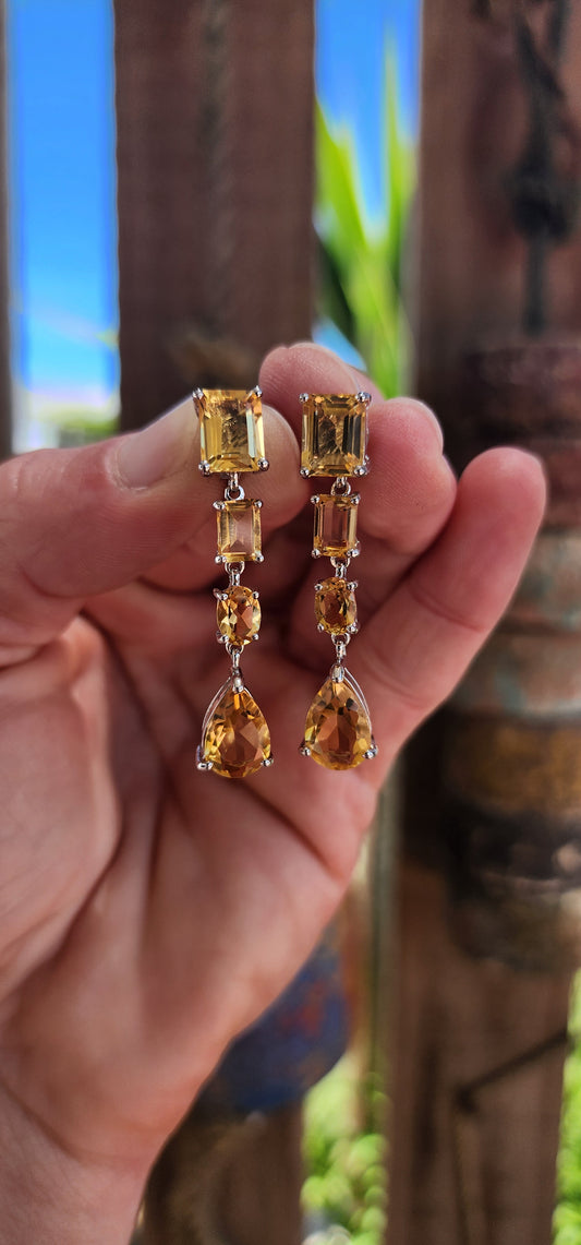 This exquisite pair of sterling silver drop earrings is a masterpiece of design and craftsmanship. Each earring is adorned with a carefully curated arrangement of radiant citrine gemstones, creating a cascade of light and warmth.