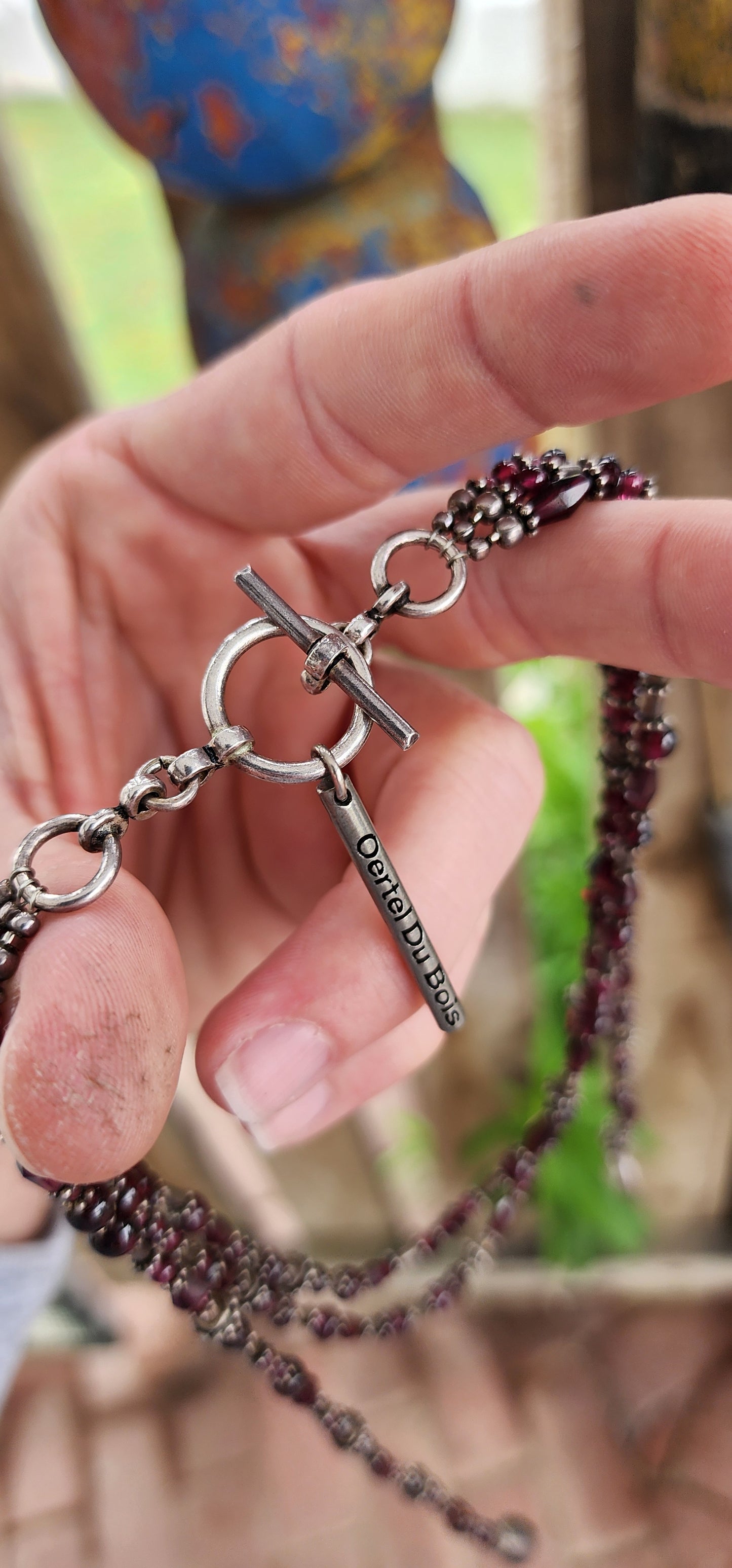 This exquisite artisan-crafted necklace is a stunning three-strand choker that seamlessly blends elegance with versatility. Its intricate design features genuine almandine garnet gemstone beads and sterling silver accents.