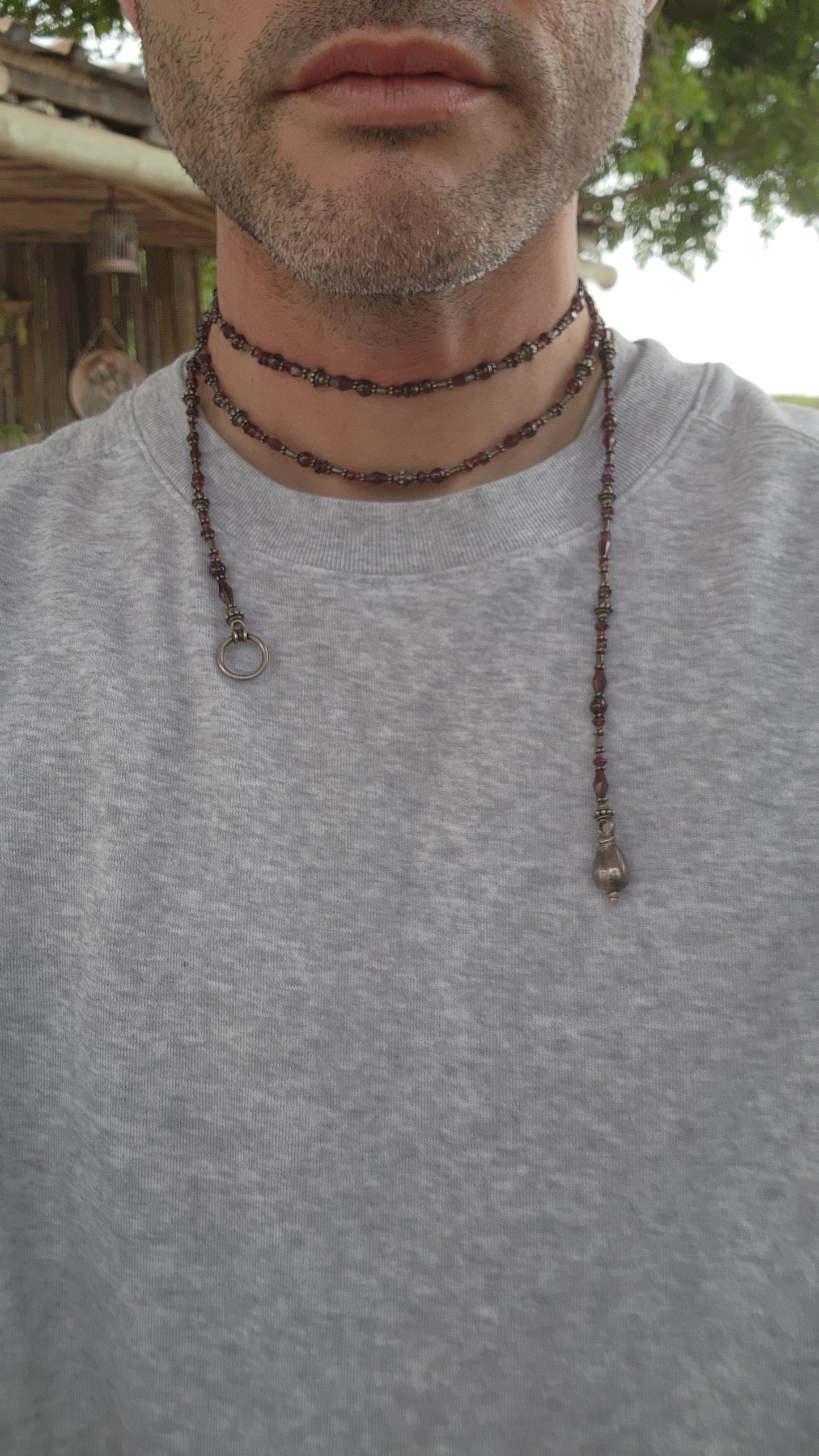 This exquisite artisan-crafted necklace is a stunning three-strand choker that seamlessly blends elegance with versatility. Its intricate design features genuine almandine garnet gemstone beads and sterling silver accents.