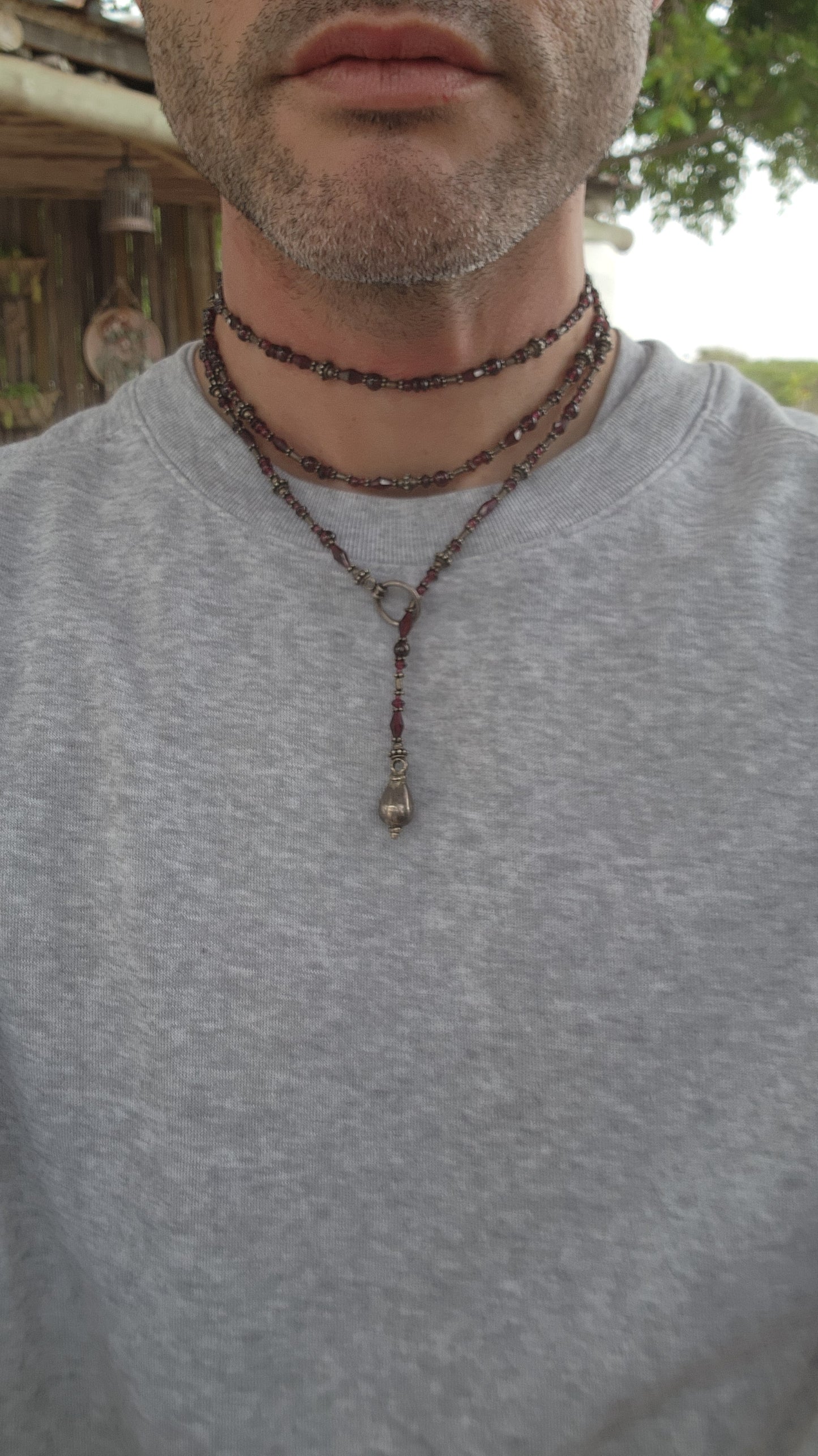 This exquisite artisan-crafted necklace is a stunning three-strand choker that seamlessly blends elegance with versatility. Its intricate design features genuine almandine garnet gemstone beads and sterling silver accents.